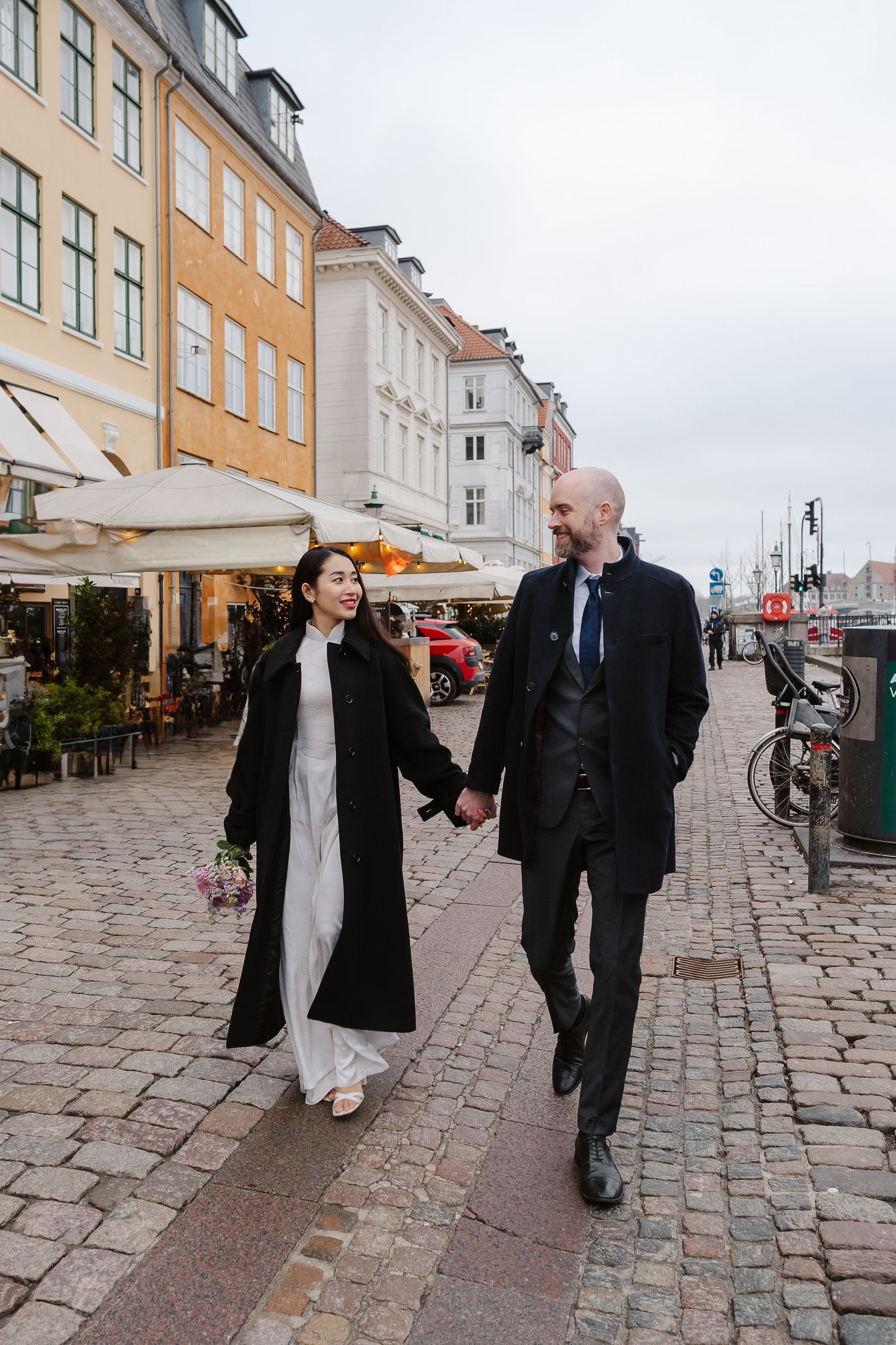 Newlyweds walking along Nyhavn Canal in Copenhagen. Denmark wedding. Scandinavian & Destination Wedding Photographer