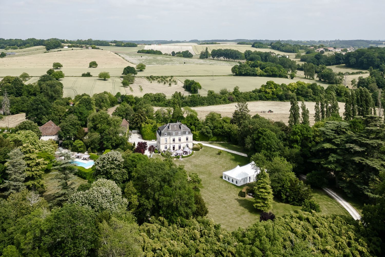 Aerial view of a French chateau wedding venue surrounded by lush green countryside and rolling fields.