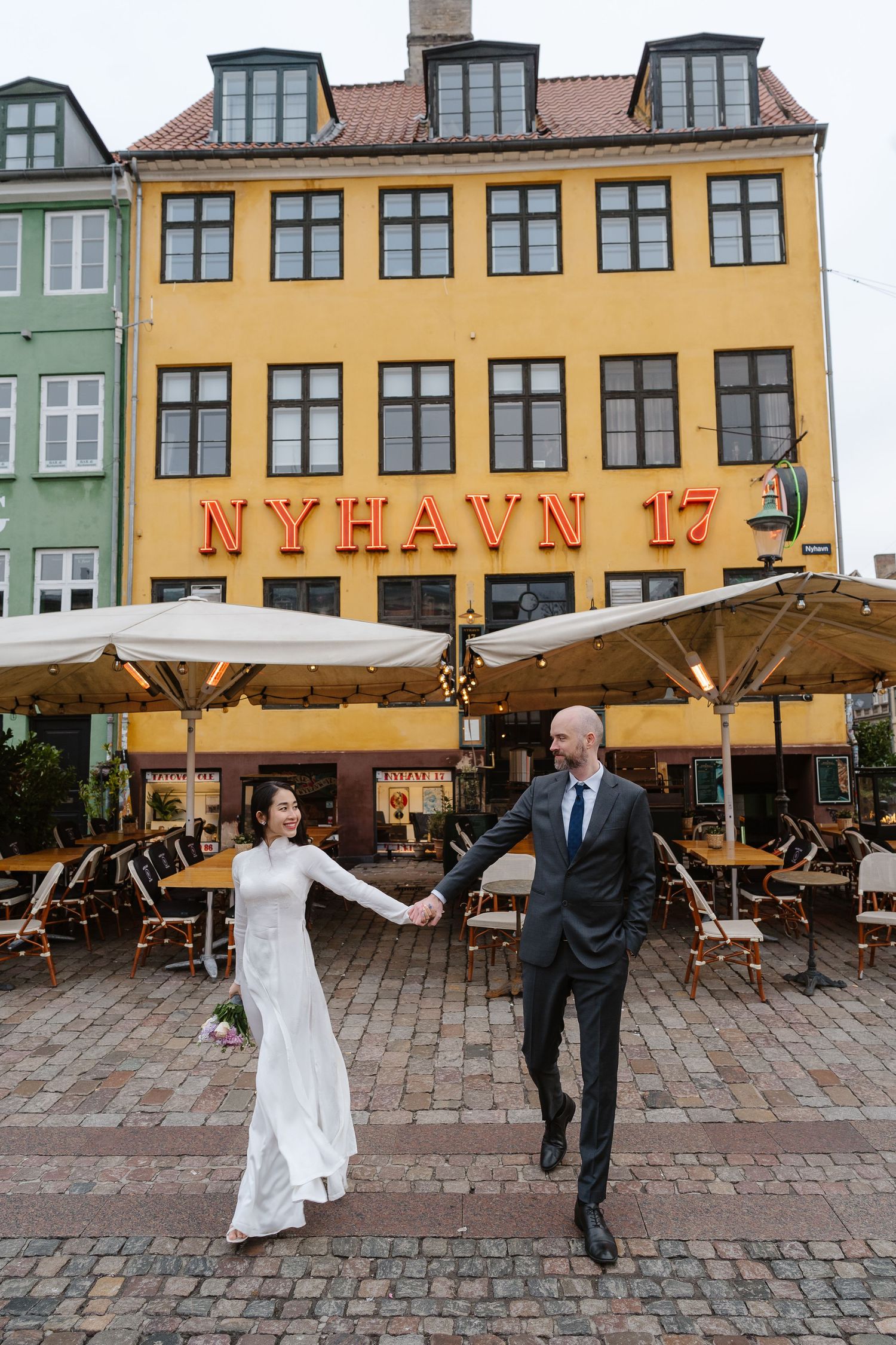 Newlyweds walking along Nyhavn Canal in Copenhagen. Denmark wedding. Scandinavian & Destination Wedding Photographer