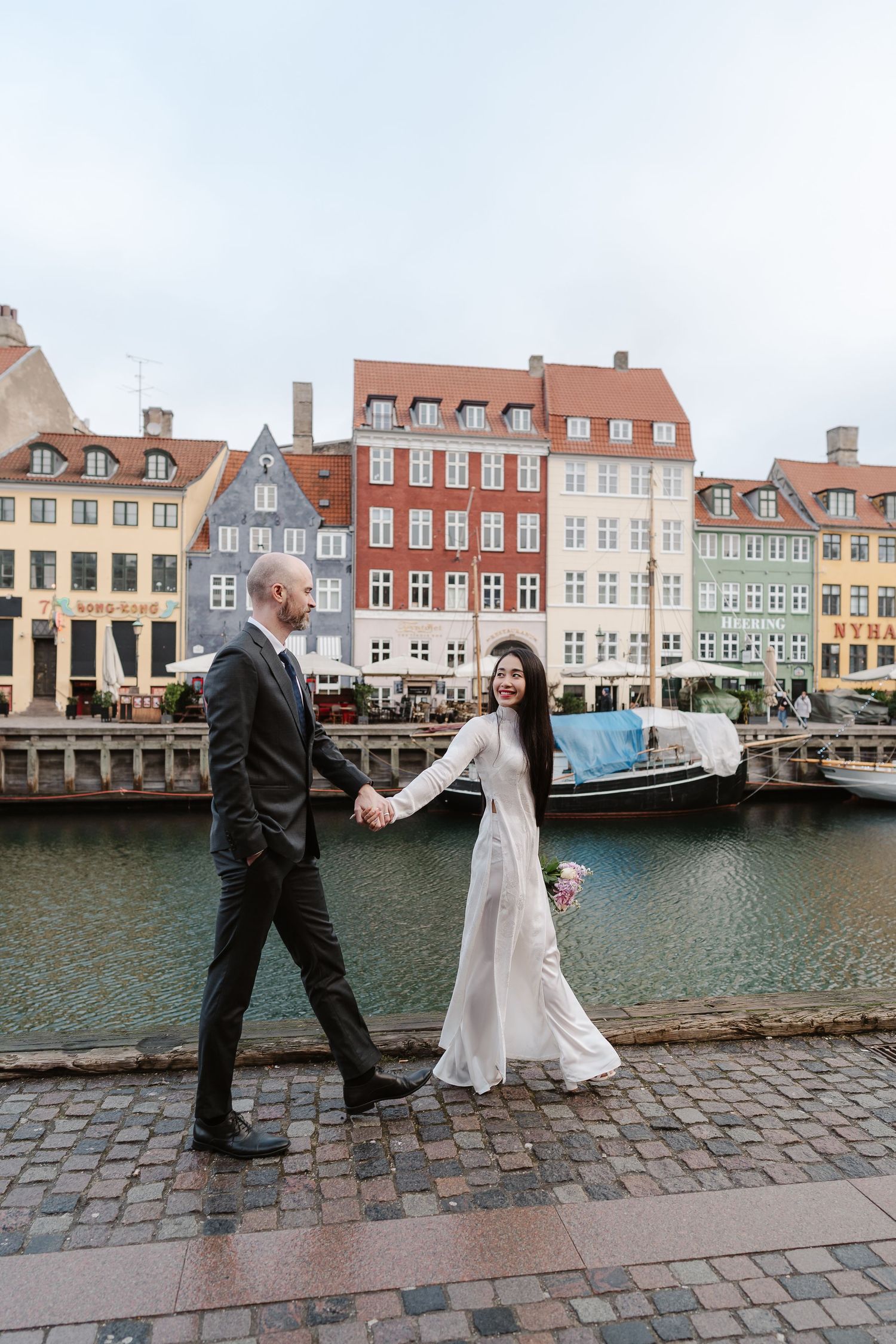 Newlyweds walking along Nyhavn Canal in Copenhagen. Denmark wedding. Scandinavian & Destination Wedding Photographer