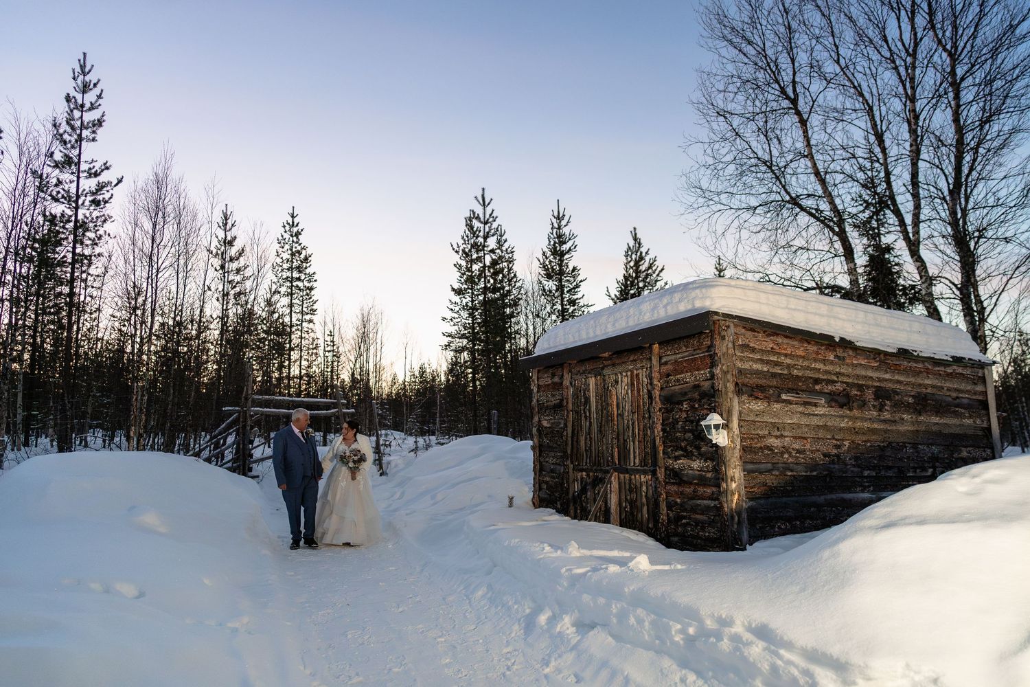 Couple walking in snow at Twilight hour. Luxury Lapland wedding photographer. Snow wedding. Lapland wedding photos. Log cabin lapland.