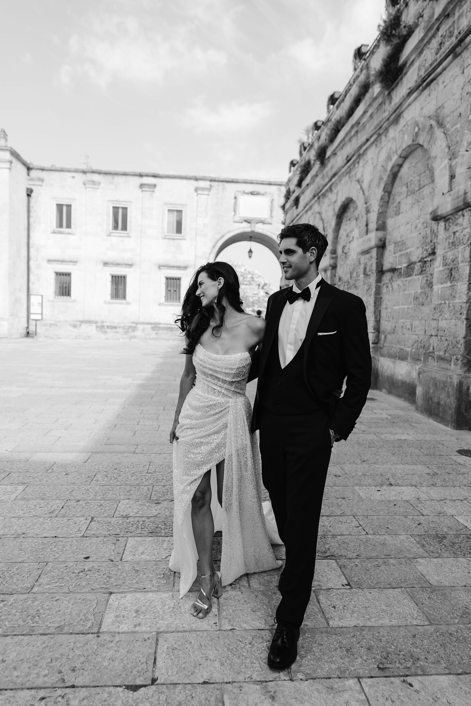 B&W elegant bride and groom walking through Matera Old Town. Italian Elopement