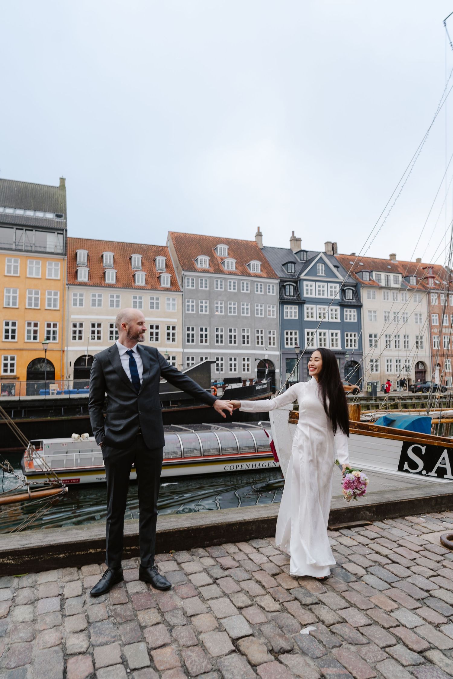 Newlyweds walking along Nyhavn Canal in Copenhagen. Denmark wedding. Scandinavian & Destination Wedding Photographer