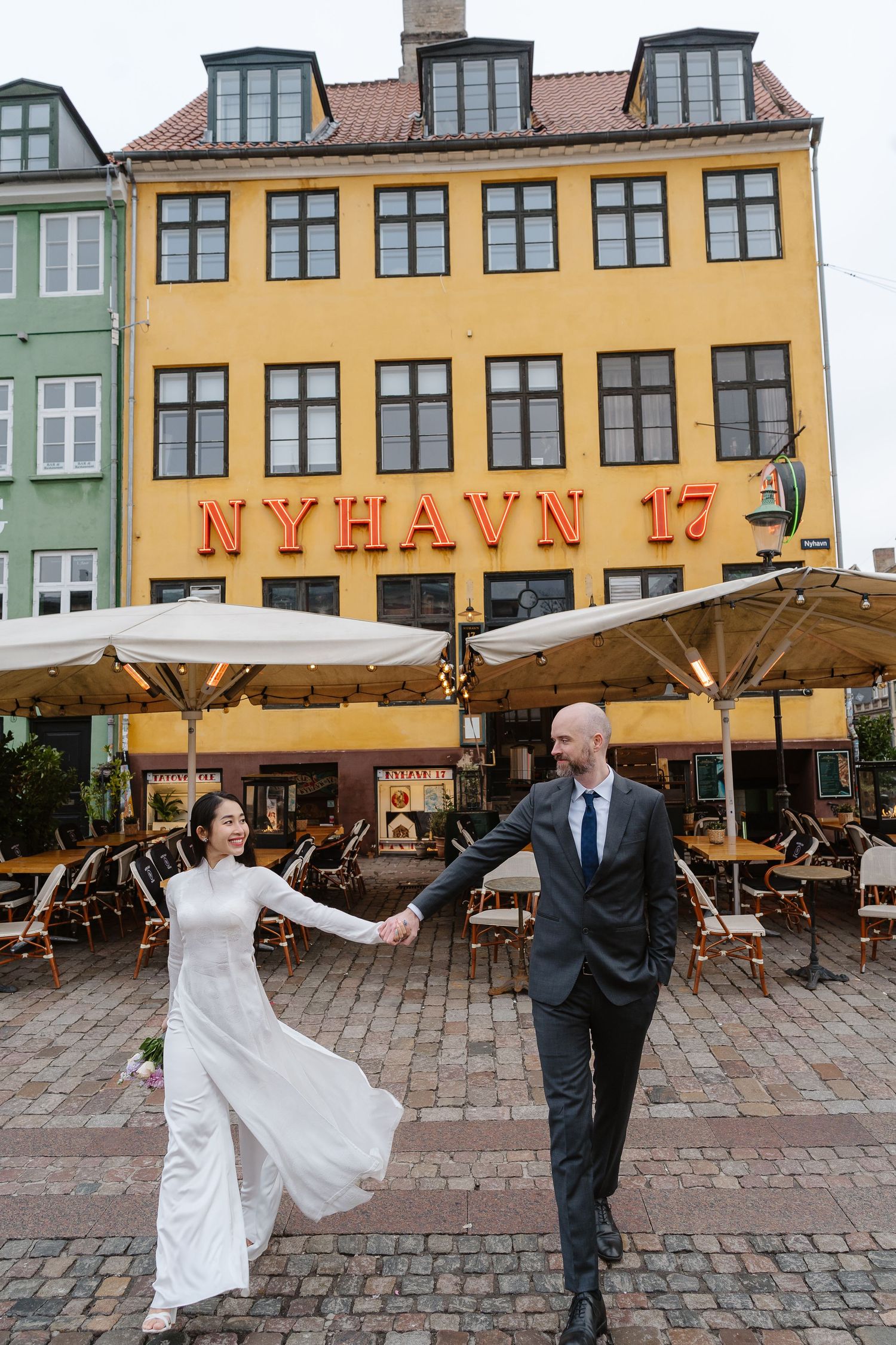 Newlyweds walking along Nyhavn Canal in Copenhagen. Denmark wedding. Scandinavian & Destination Wedding Photographer