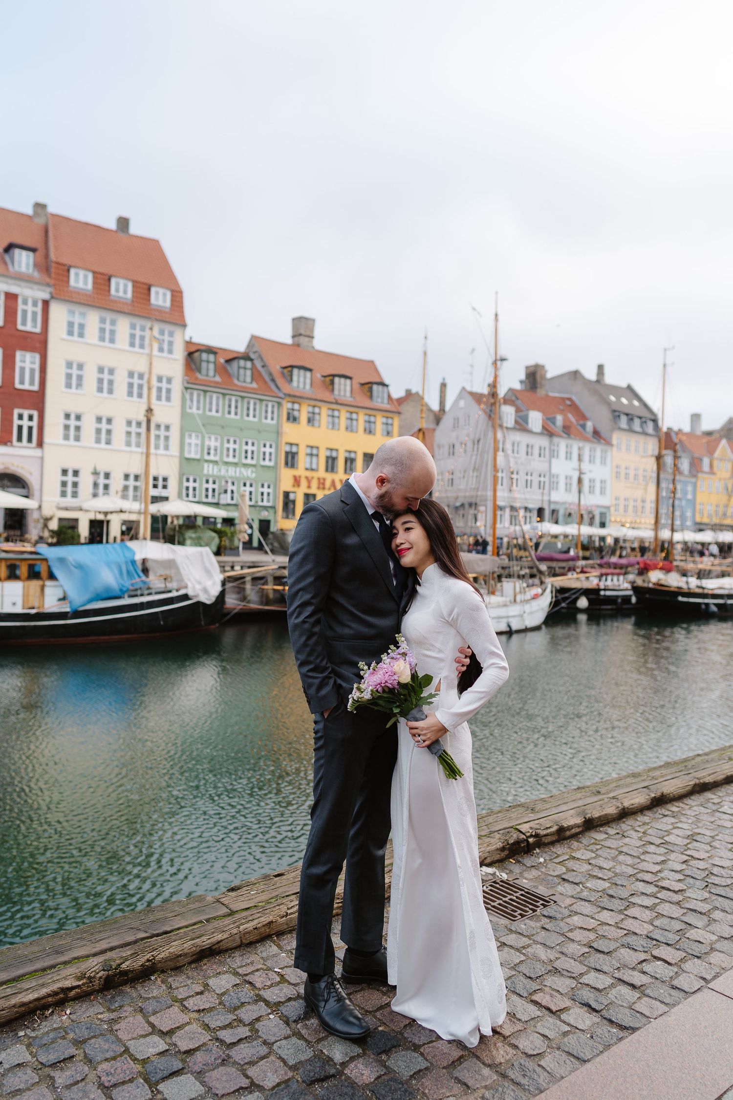 Newlyweds walking along Nyhavn Canal in Copenhagen. Denmark wedding. Scandinavian & Destination Wedding Photographer