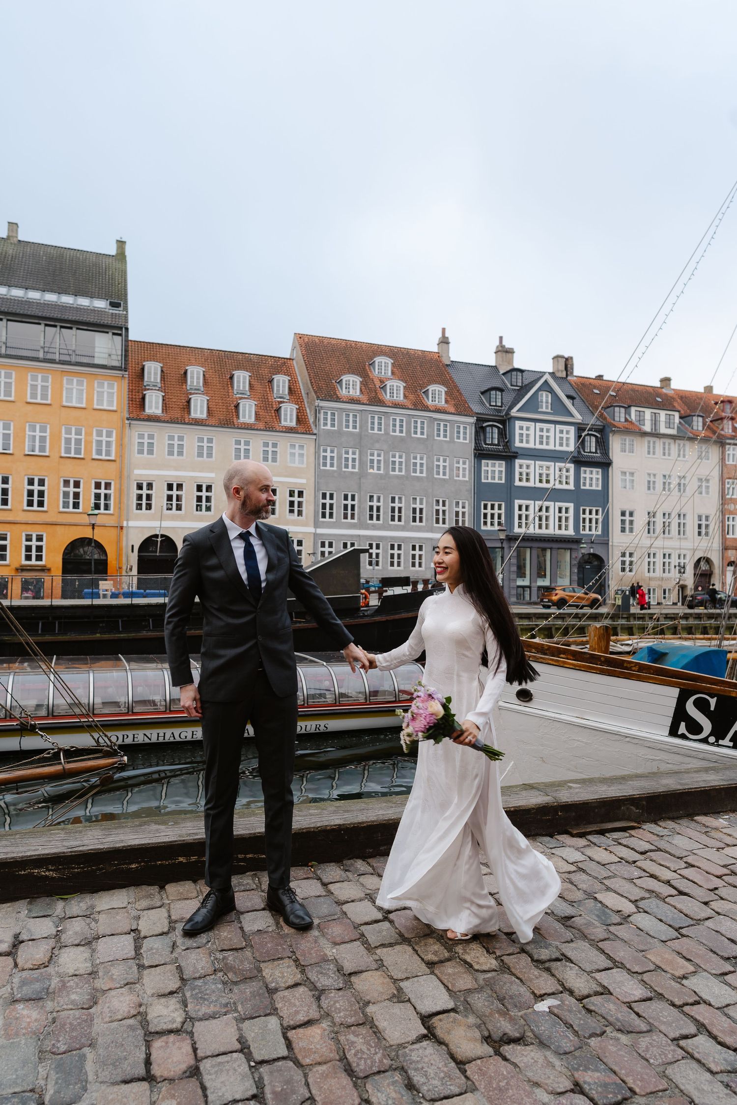 Newlyweds walking along Nyhavn Canal in Copenhagen. Denmark wedding. Scandinavian & Destination Wedding Photographer