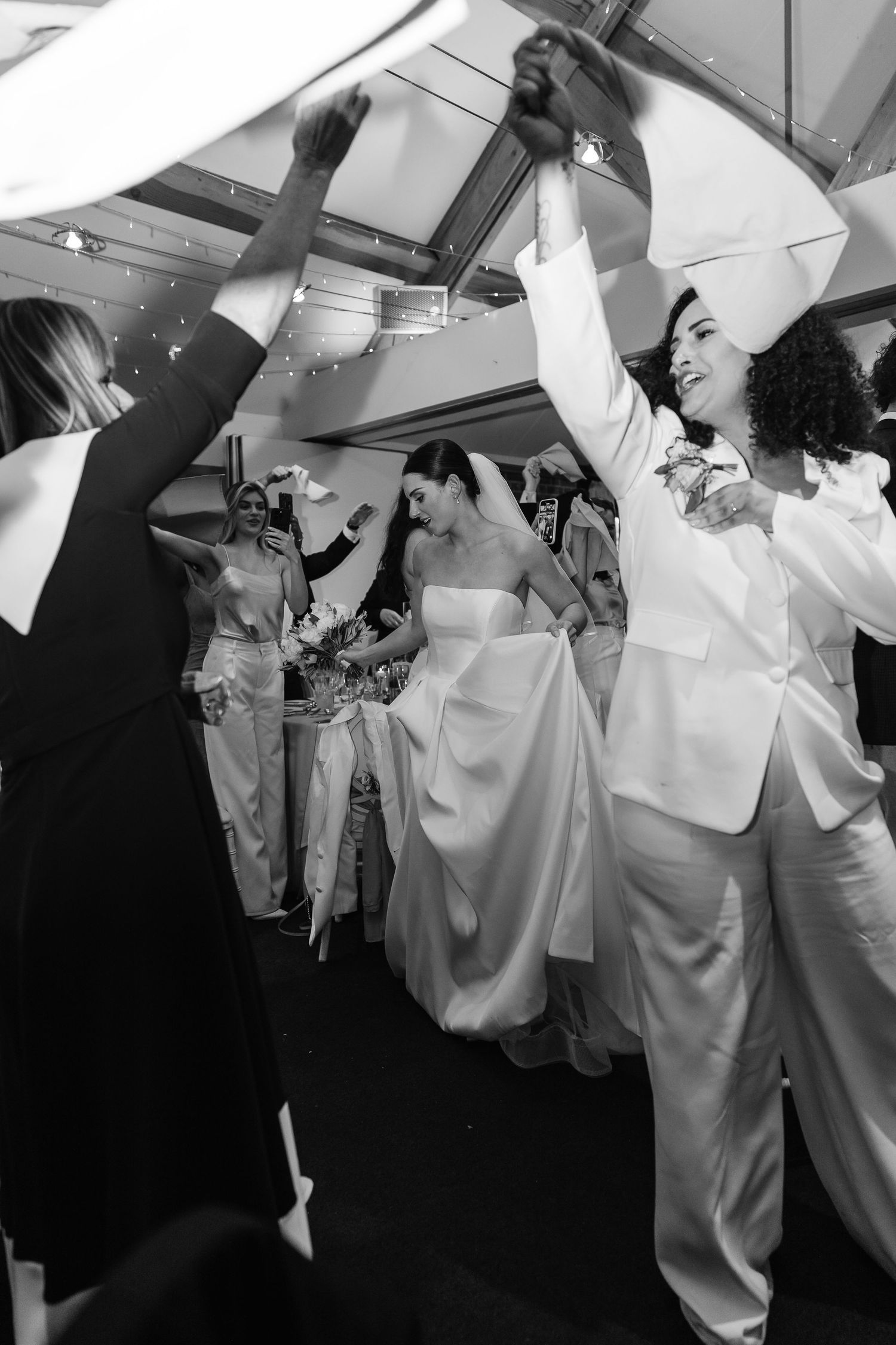 Black and white photo of a same-sex couple dancing joyfully at their wedding reception.