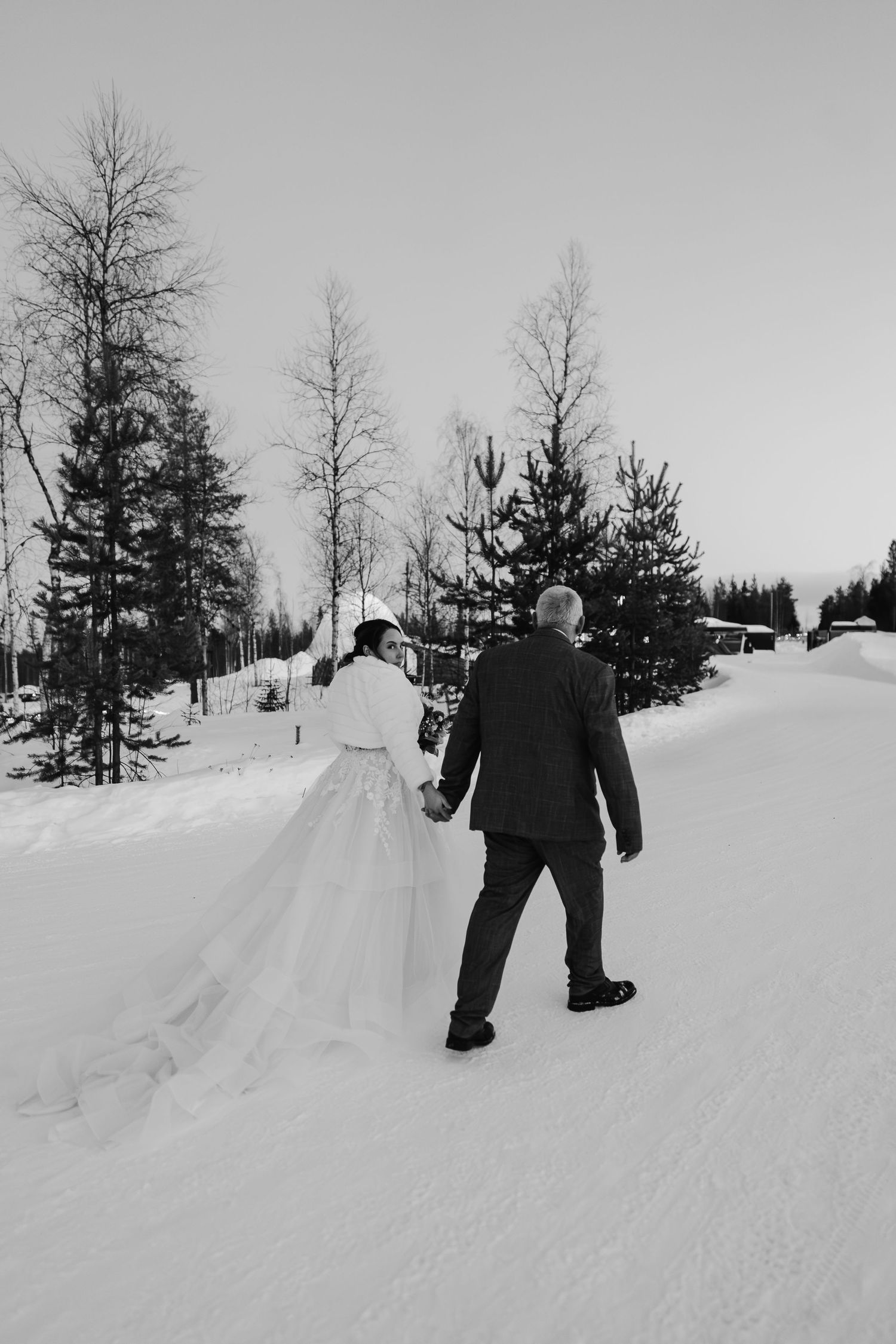 Couple candidly walking through forest with pink skies. Luxury Lapland wedding photographer. Snow wedding. Mountain Wedding. dream wedding