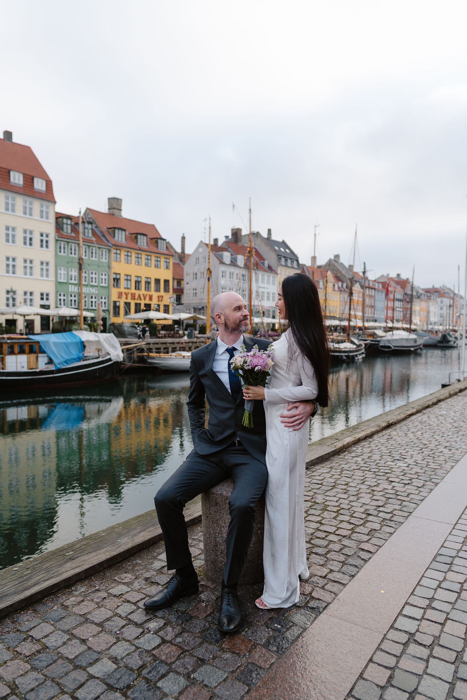 Newlyweds walking along Nyhavn Canal in Copenhagen. Denmark wedding. Scandinavian & Destination Wedding Photographer