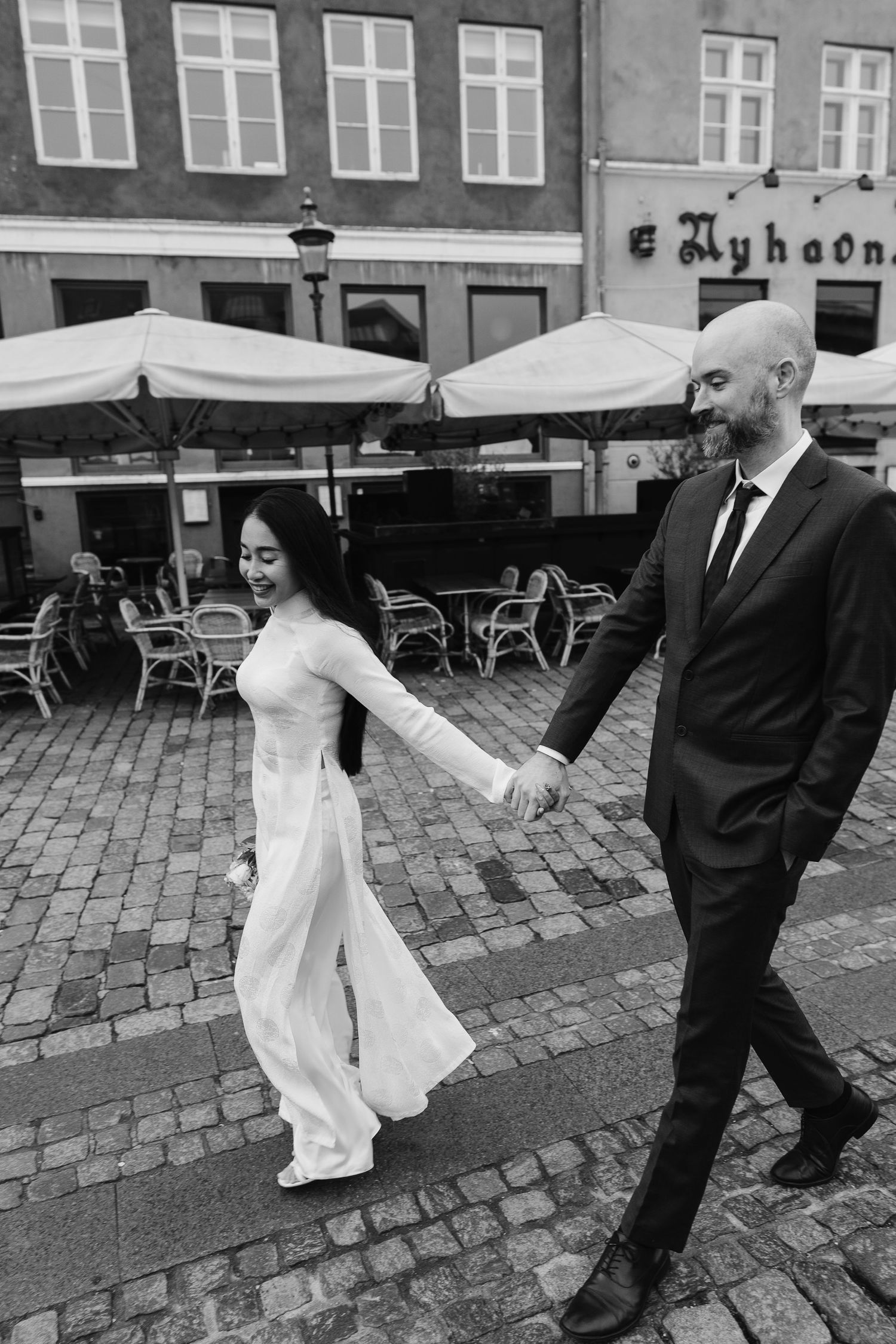 Newlyweds walking along Nyhavn Canal in Copenhagen. Denmark wedding. Scandinavian & Destination Wedding Photographer