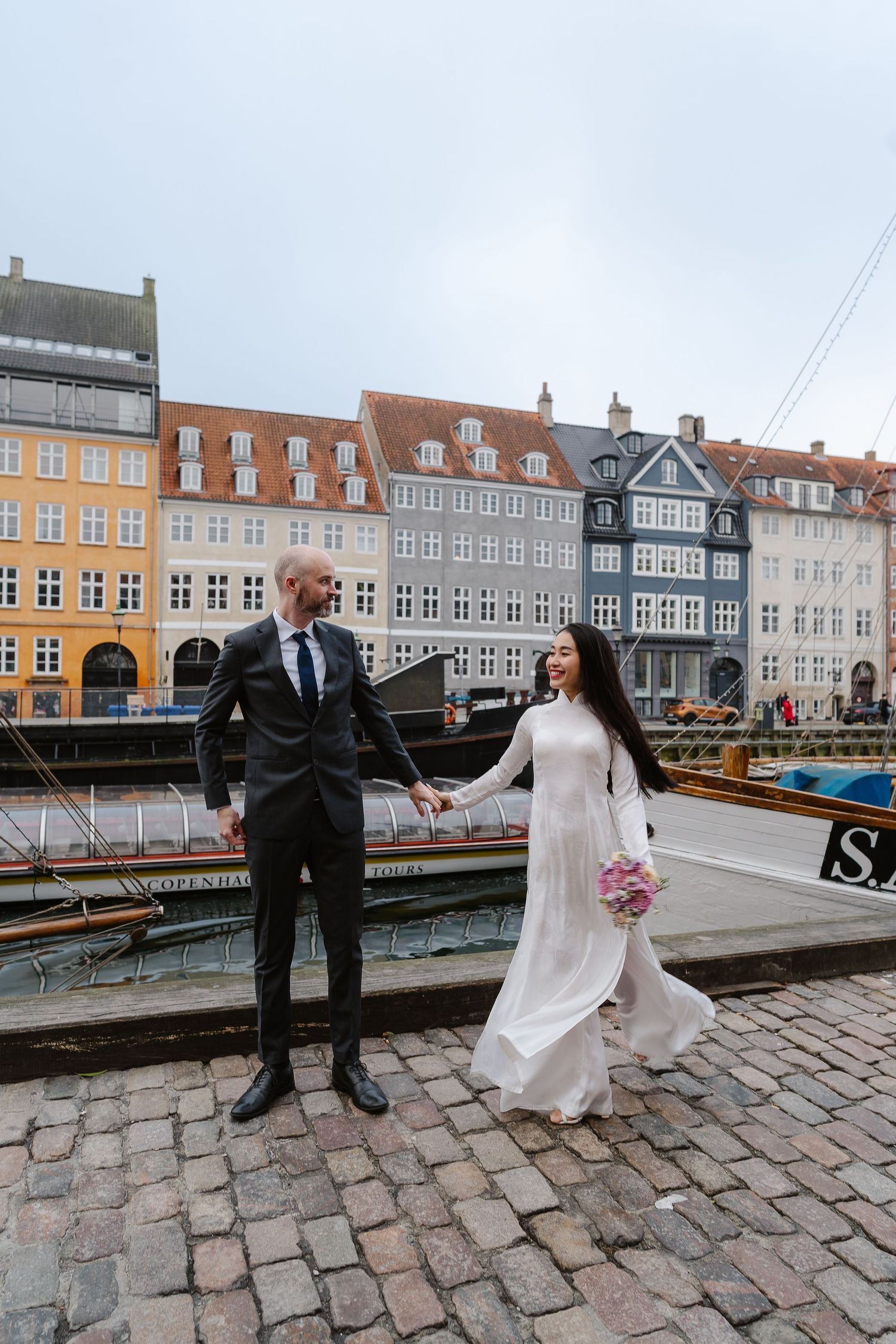 Newlyweds walking along Nyhavn Canal in Copenhagen. Denmark wedding. Scandinavian & Destination Wedding Photographer