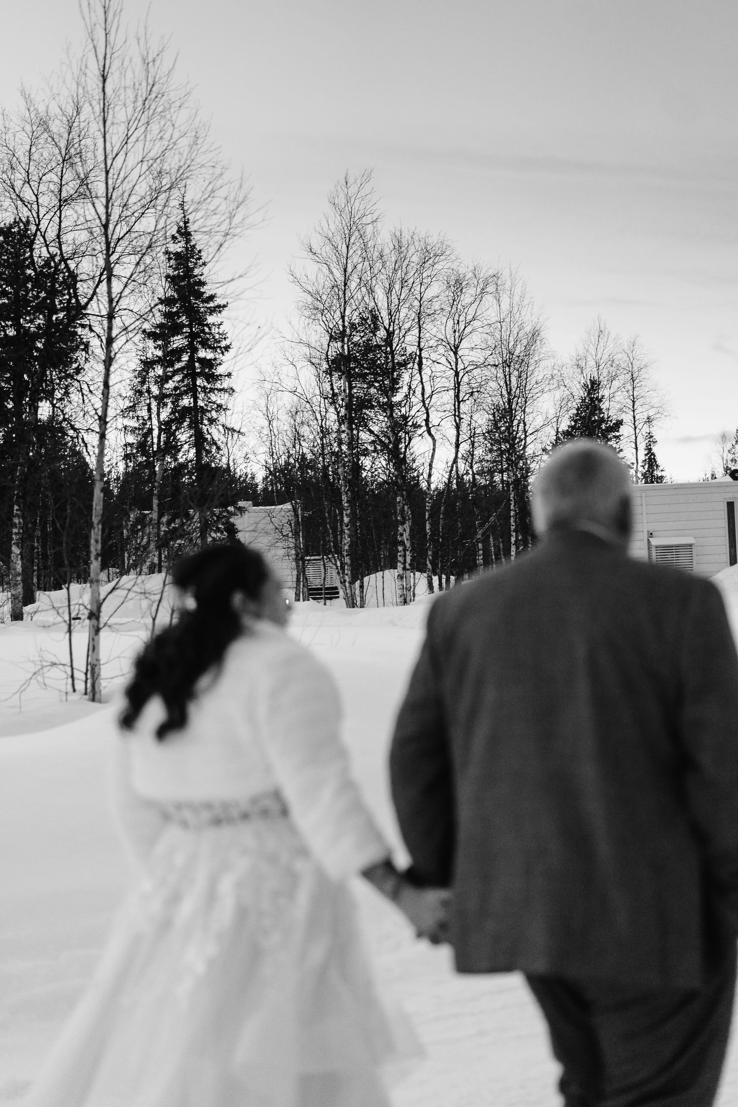 Couple candidly walking through forest at Twilight hour. Luxury Lapland wedding photographer. Snow wedding. Mountain Wedding.