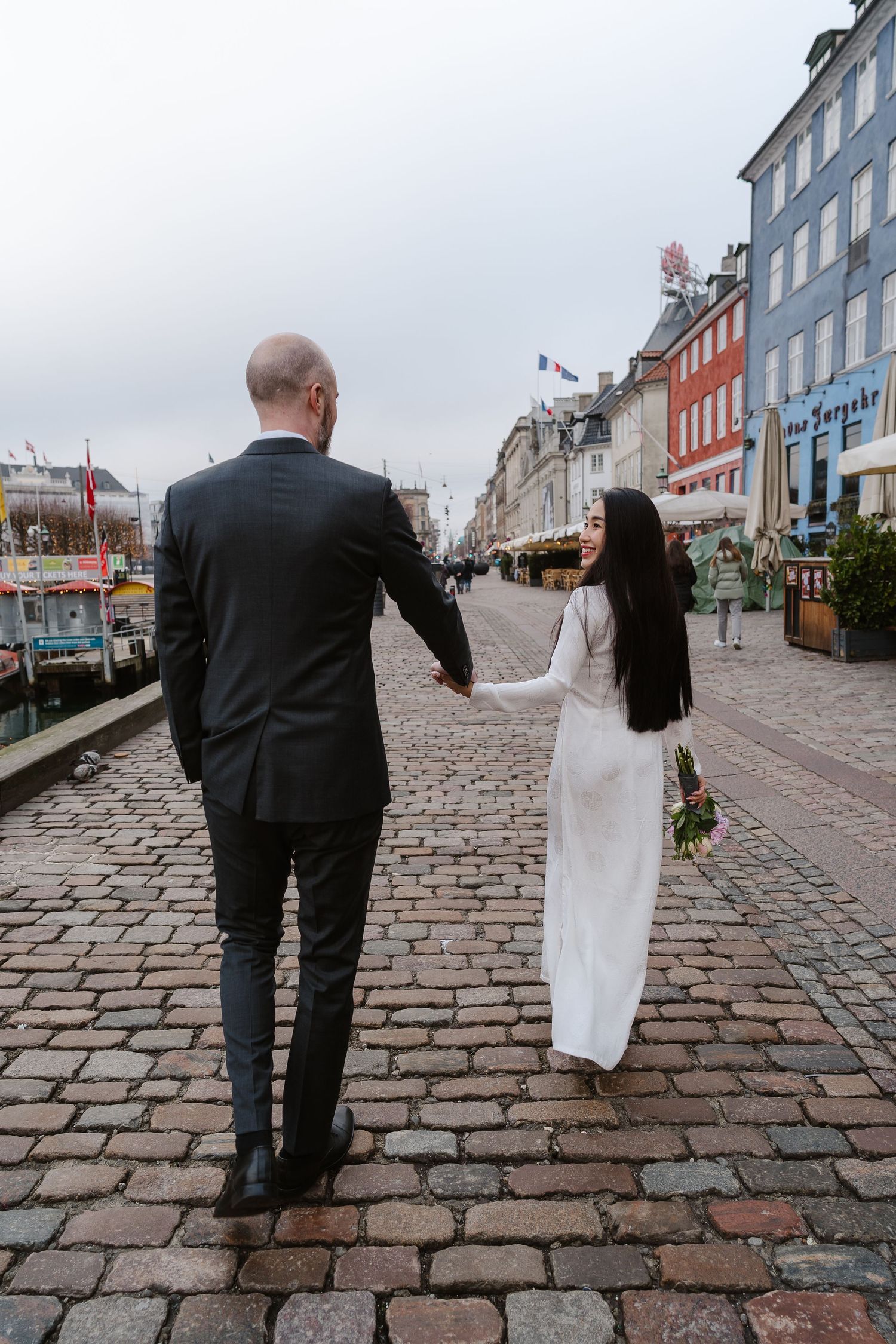 Newlyweds walking along Nyhavn Canal in Copenhagen. Denmark wedding. Scandinavian & Destination Wedding Photographer
