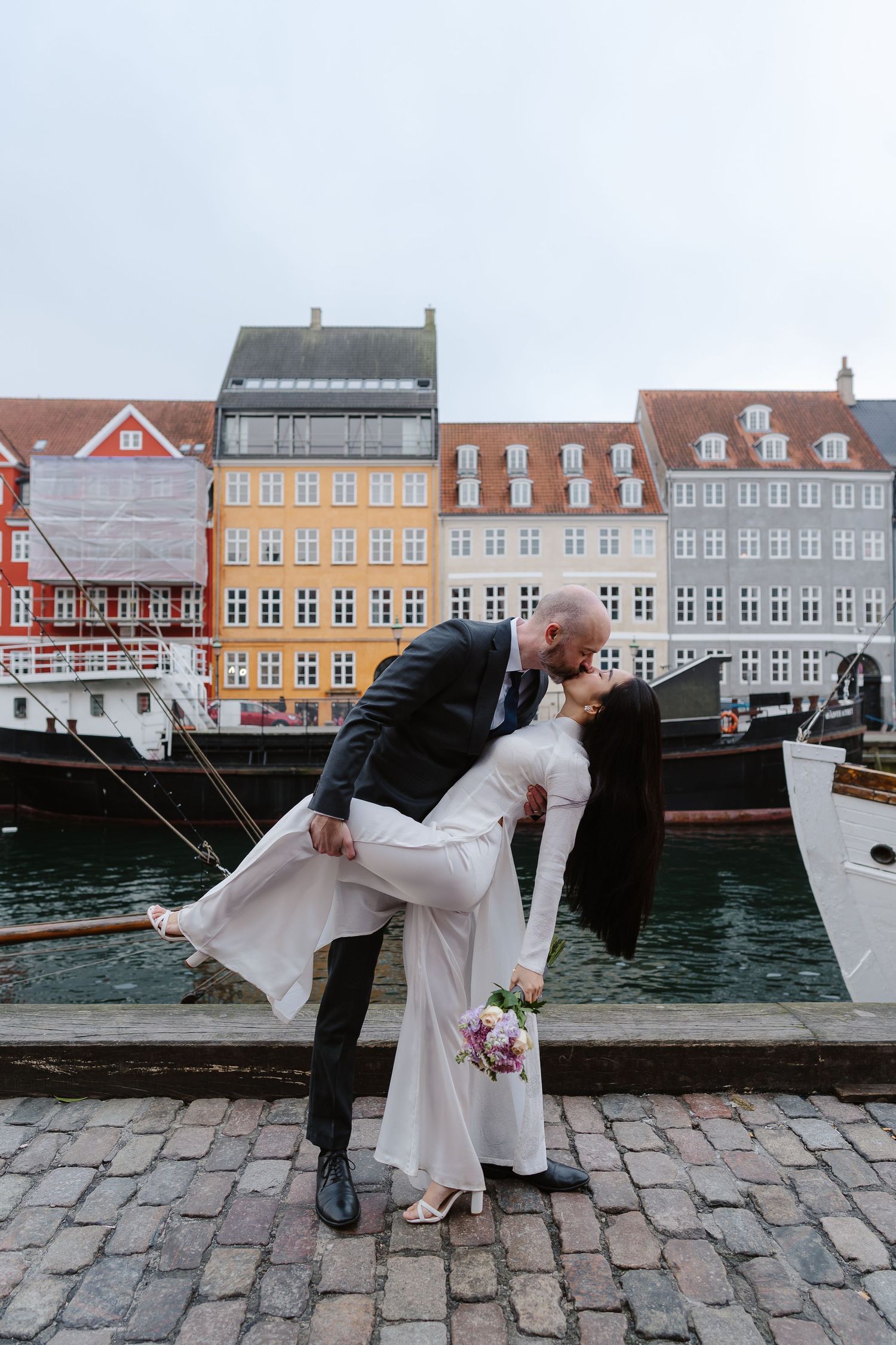 Newlyweds walking along Nyhavn Canal in Copenhagen. Denmark wedding. Scandinavian & Destination Wedding Photographer