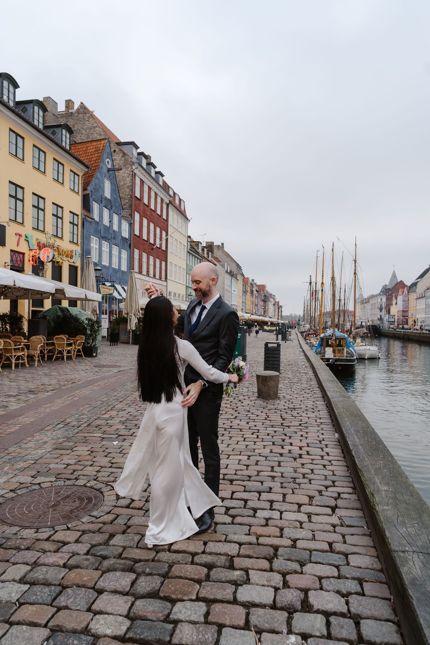 Newlyweds walking along Nyhavn Canal in Copenhagen. Denmark wedding. Scandinavian & Destination Wedding Photographer