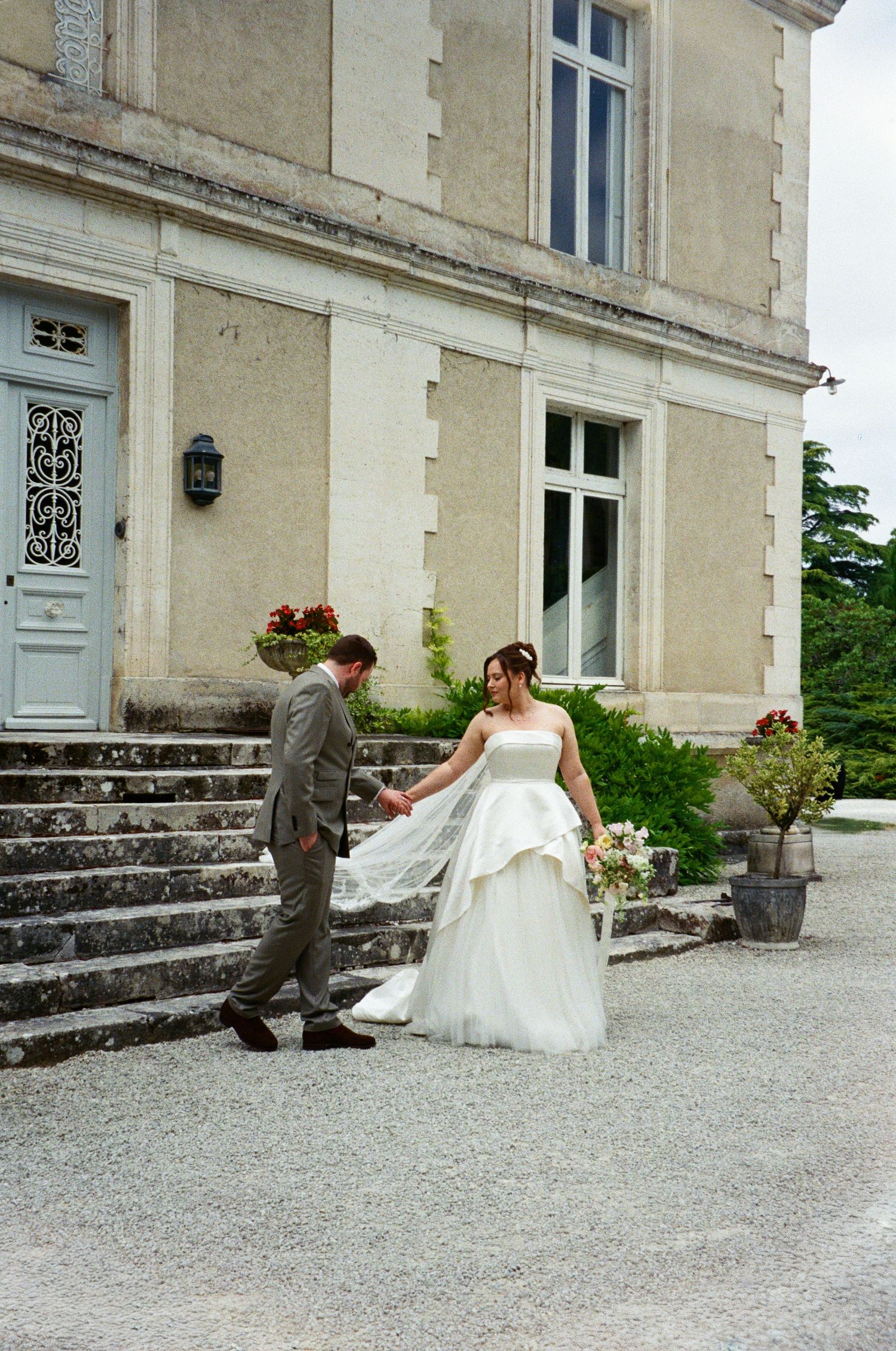 Bride and groom hold hands outside a elegant French chateau on their wedding day.