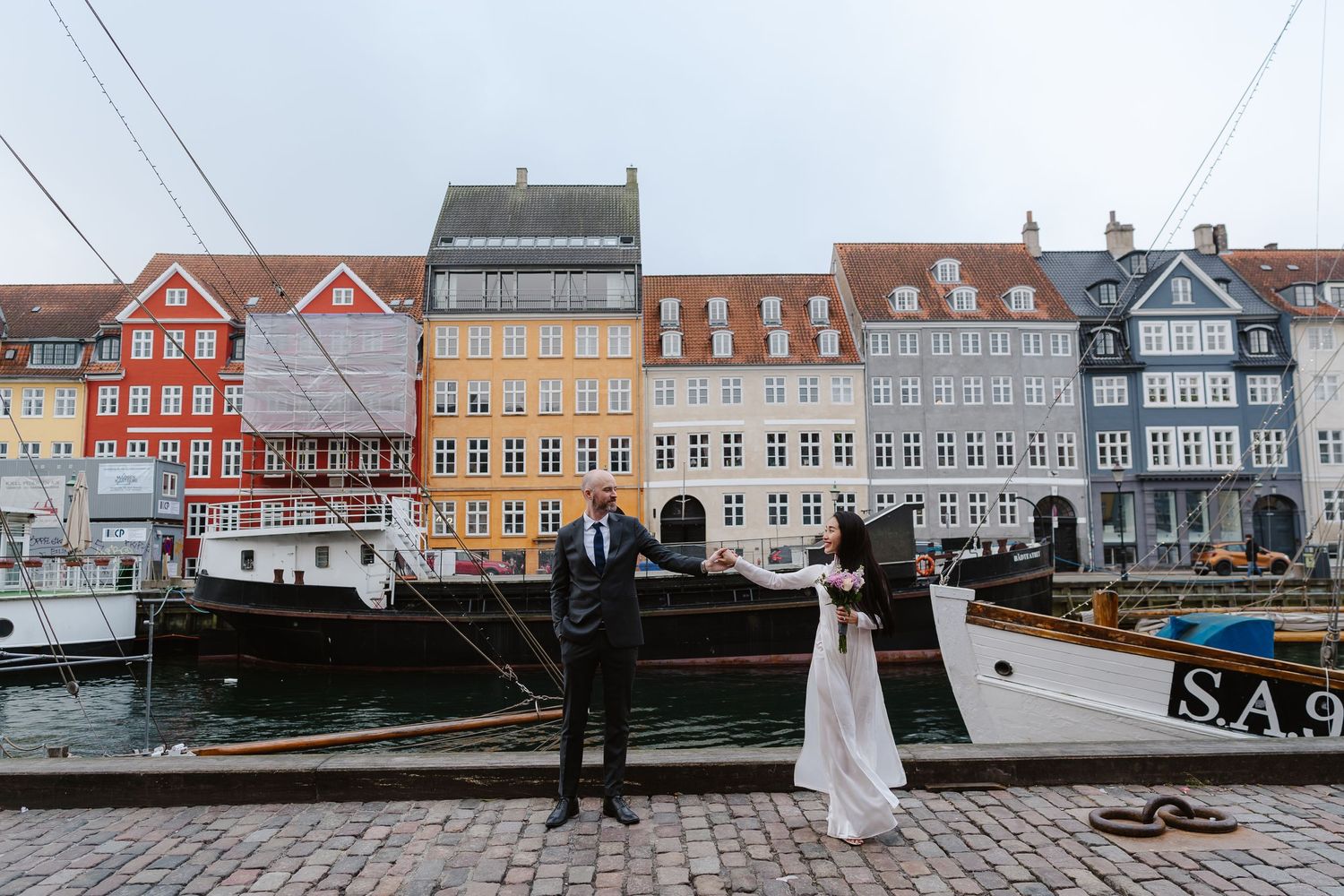 Newlyweds walking along Nyhavn Canal in Copenhagen. Denmark wedding. Scandinavian & Destination Wedding Photographer