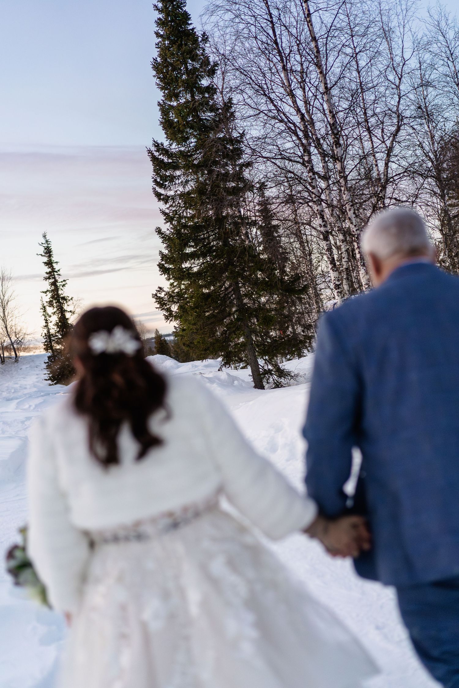 Couple candidly walking through forest at Snow Chapel, Levi. Luxury Lapland wedding photographer. Snow wedding. Mountain Wedding.