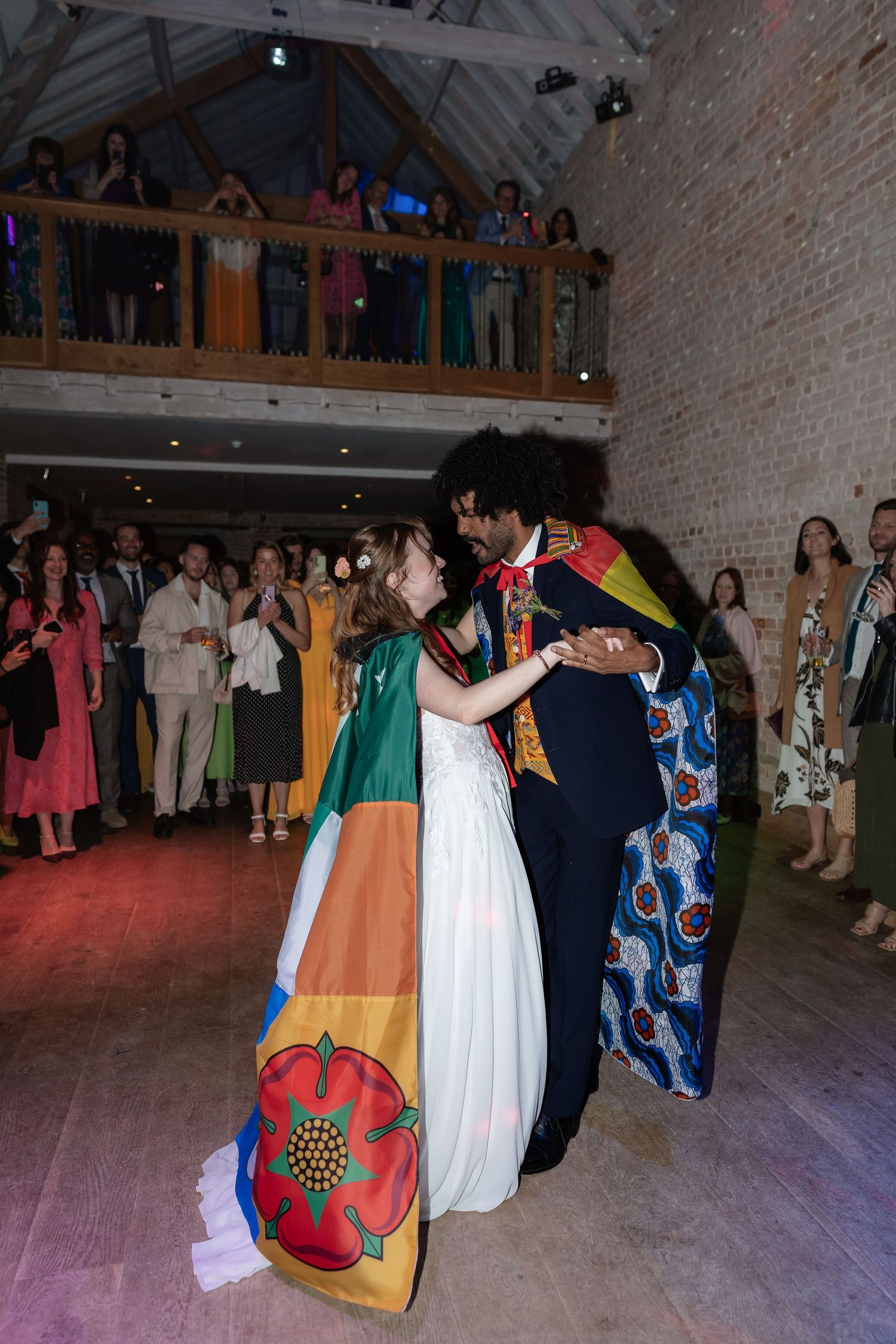 Bride and groom share intimate first dance wrapped in colorful international flags.