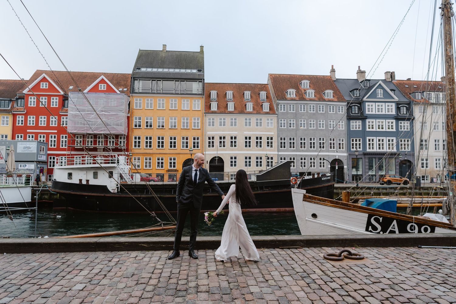 Newlyweds walking along Nyhavn Canal in Copenhagen. Denmark wedding. Scandinavian & Destination Wedding Photographer