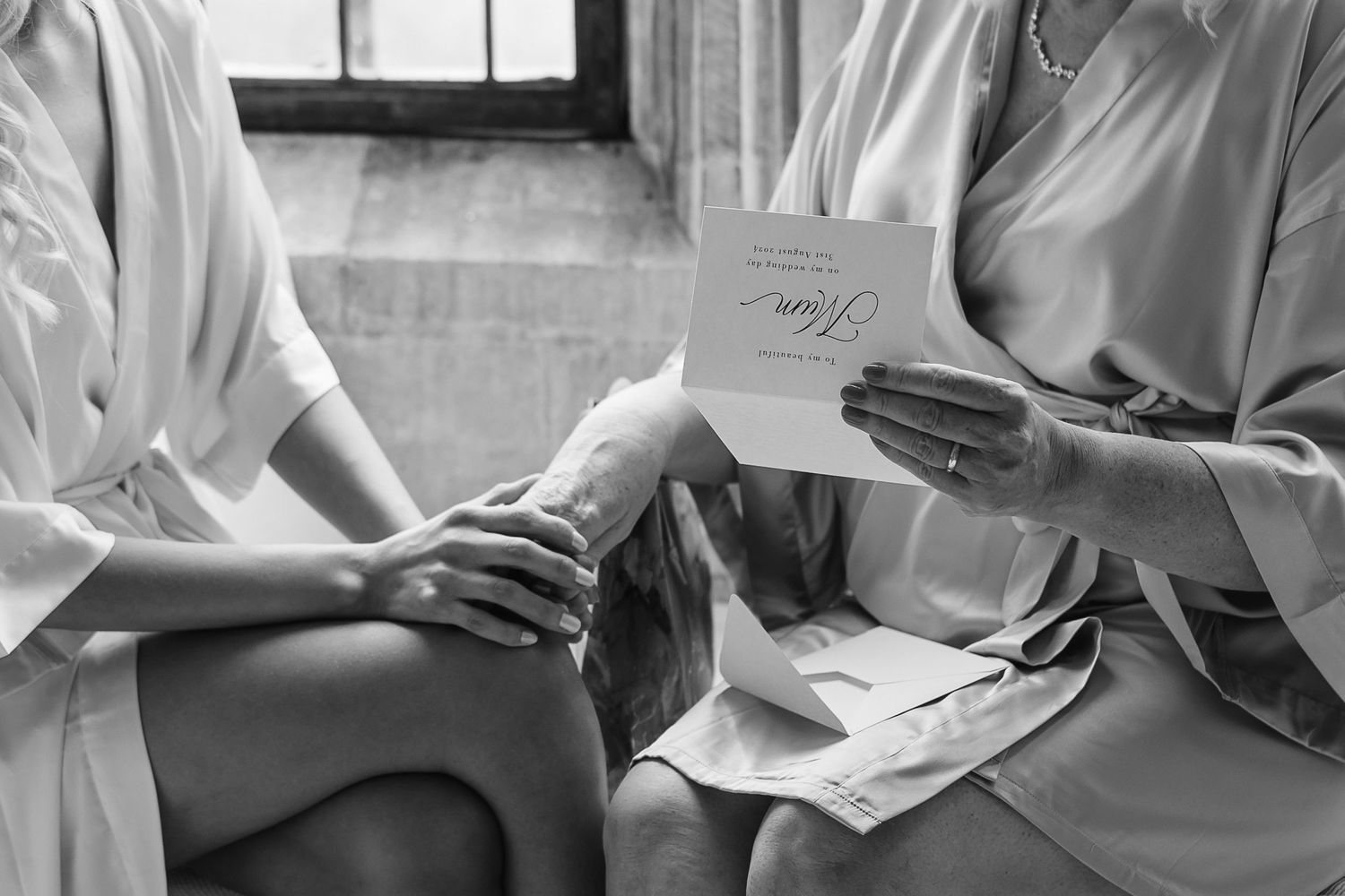 Black and white photo of bridesmaids reading a heartfelt wedding card together while seated.