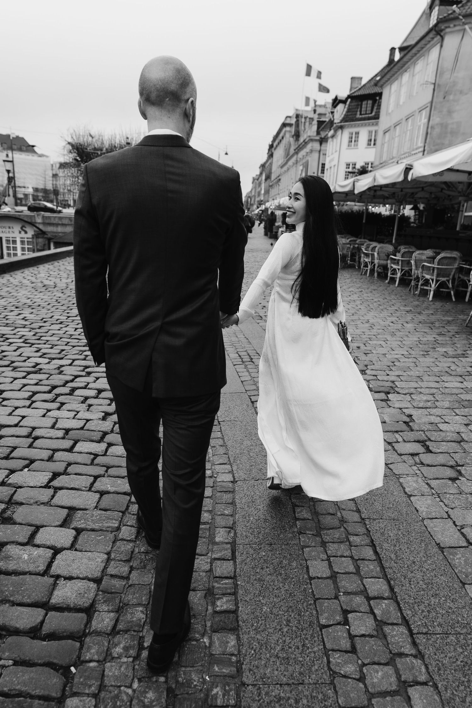 Newlyweds walking along Nyhavn Canal in Copenhagen. Denmark wedding. Scandinavian & Destination Wedding Photographer
