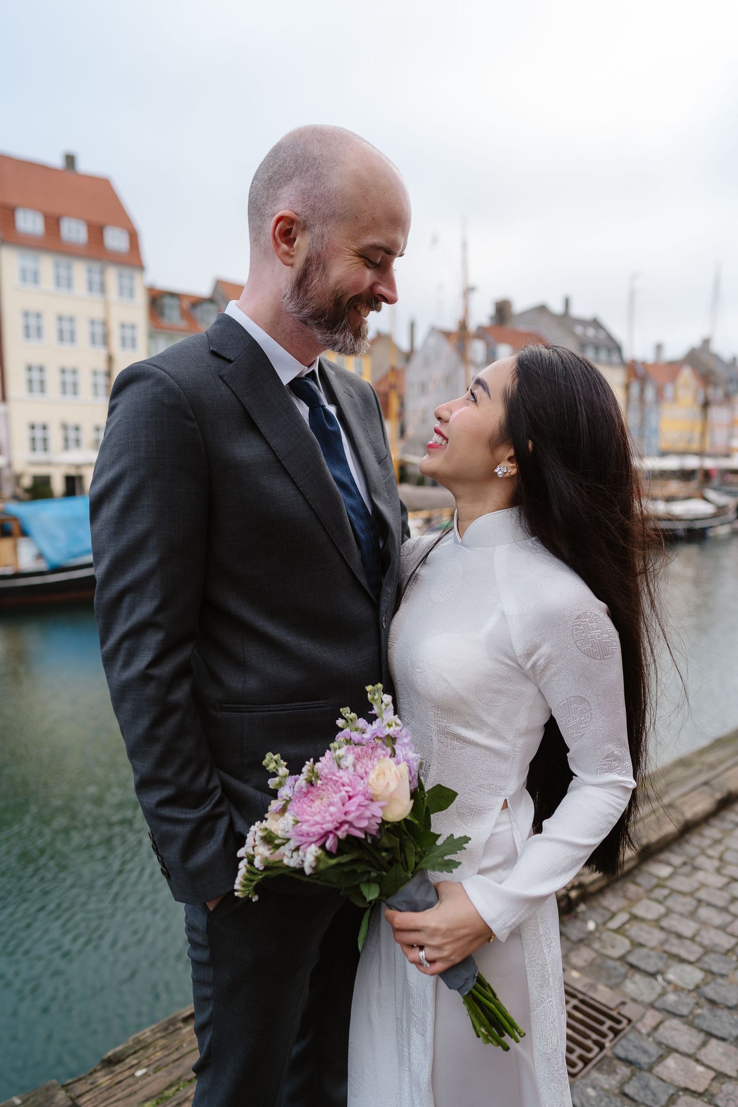 Newlyweds walking along Nyhavn Canal in Copenhagen. Denmark wedding. Scandinavian & Destination Wedding Photographer