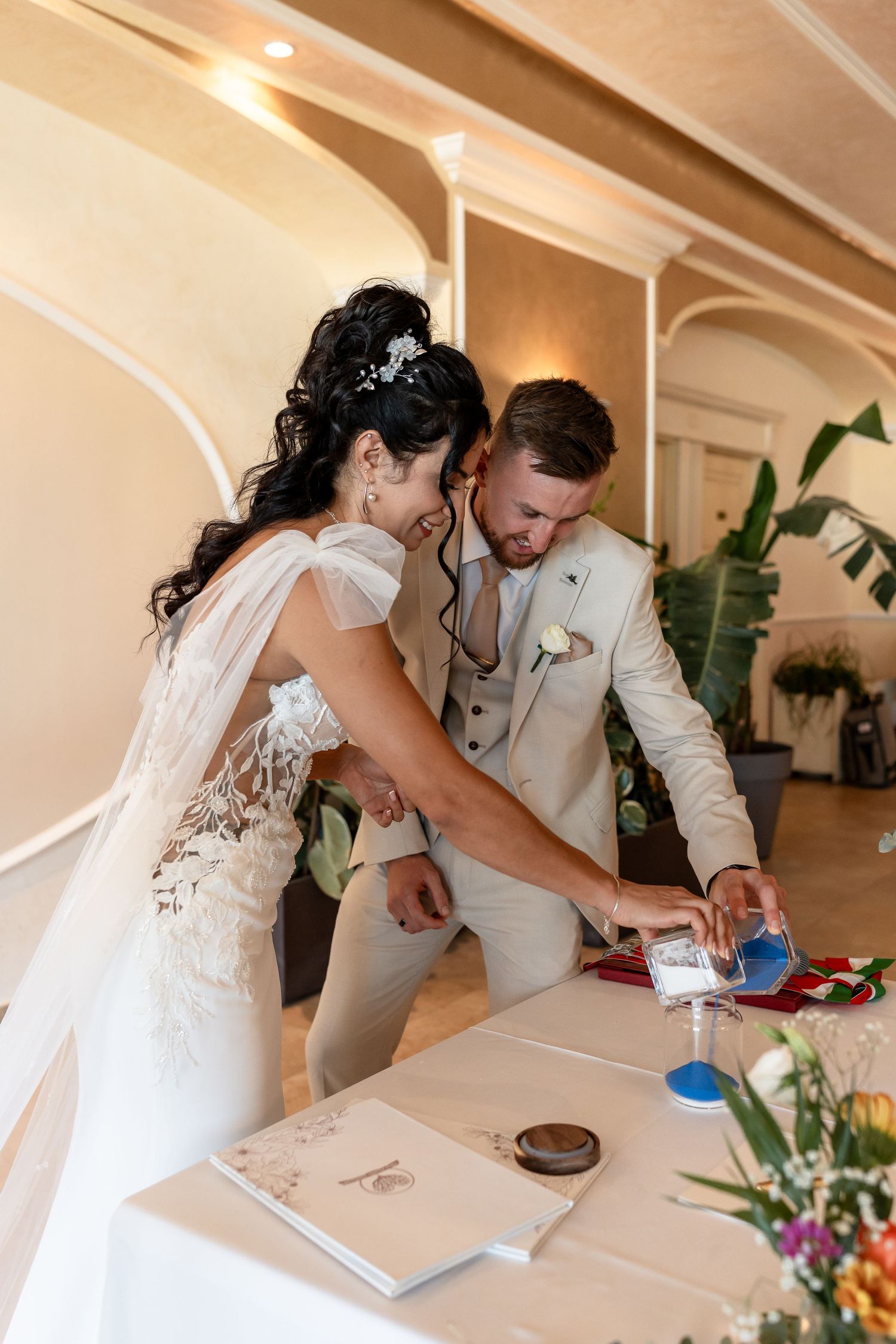Bride and groom performing a sand unity ceremony at their elegant indoor wedding reception.