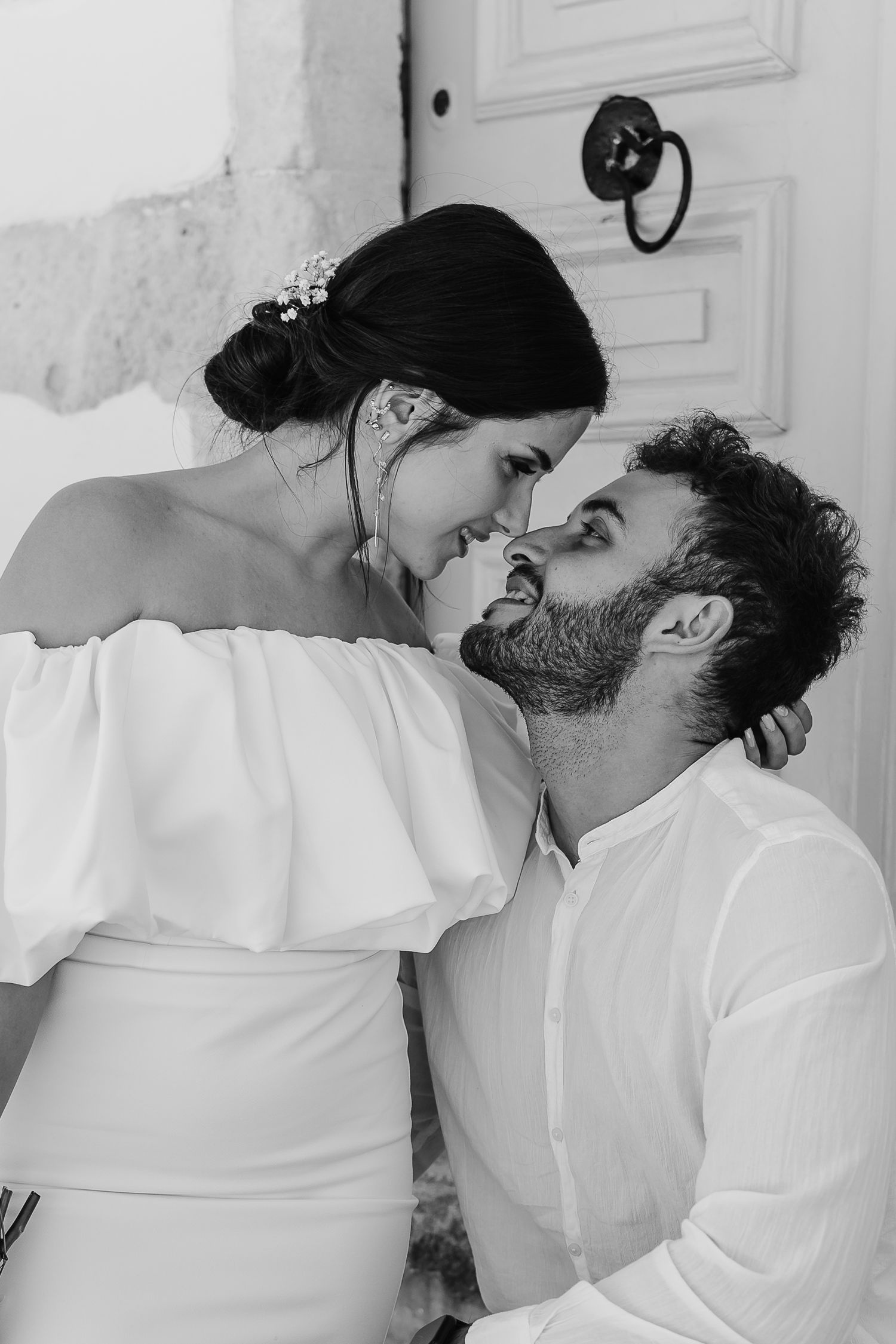 Black and white close-up of bride and groom nearly kissing by a vintage wooden door.