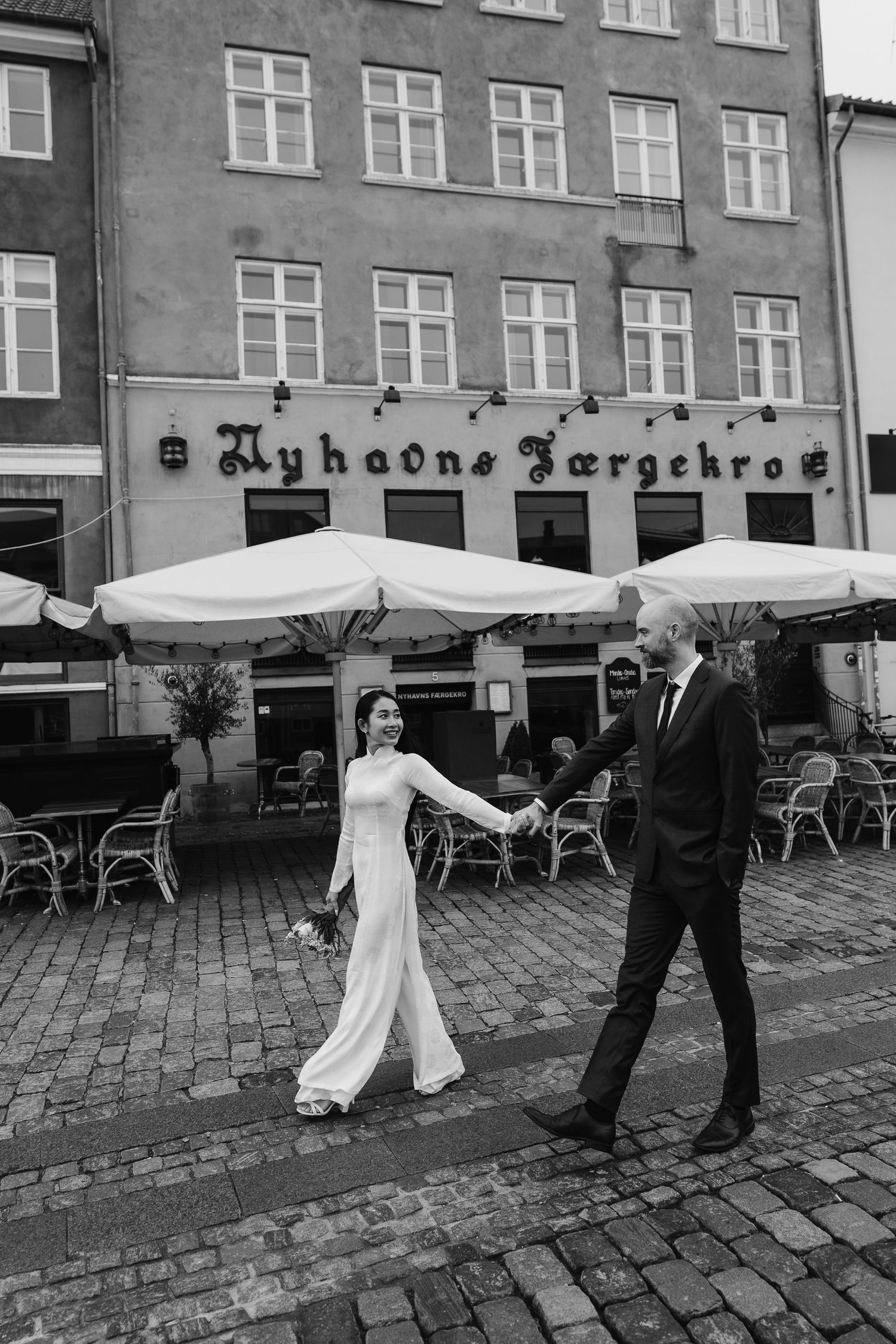 Newlyweds walking along Nyhavn Canal in Copenhagen. Denmark wedding. Scandinavian & Destination Wedding Photographer