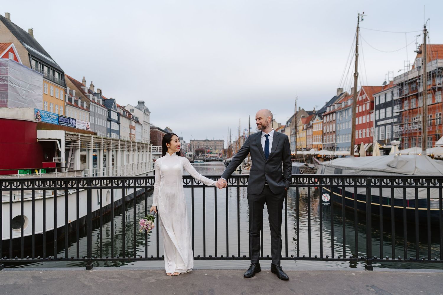 Newlyweds walking along Nyhavn Canal in Copenhagen. Denmark wedding. Scandinavian & Destination Wedding Photographer