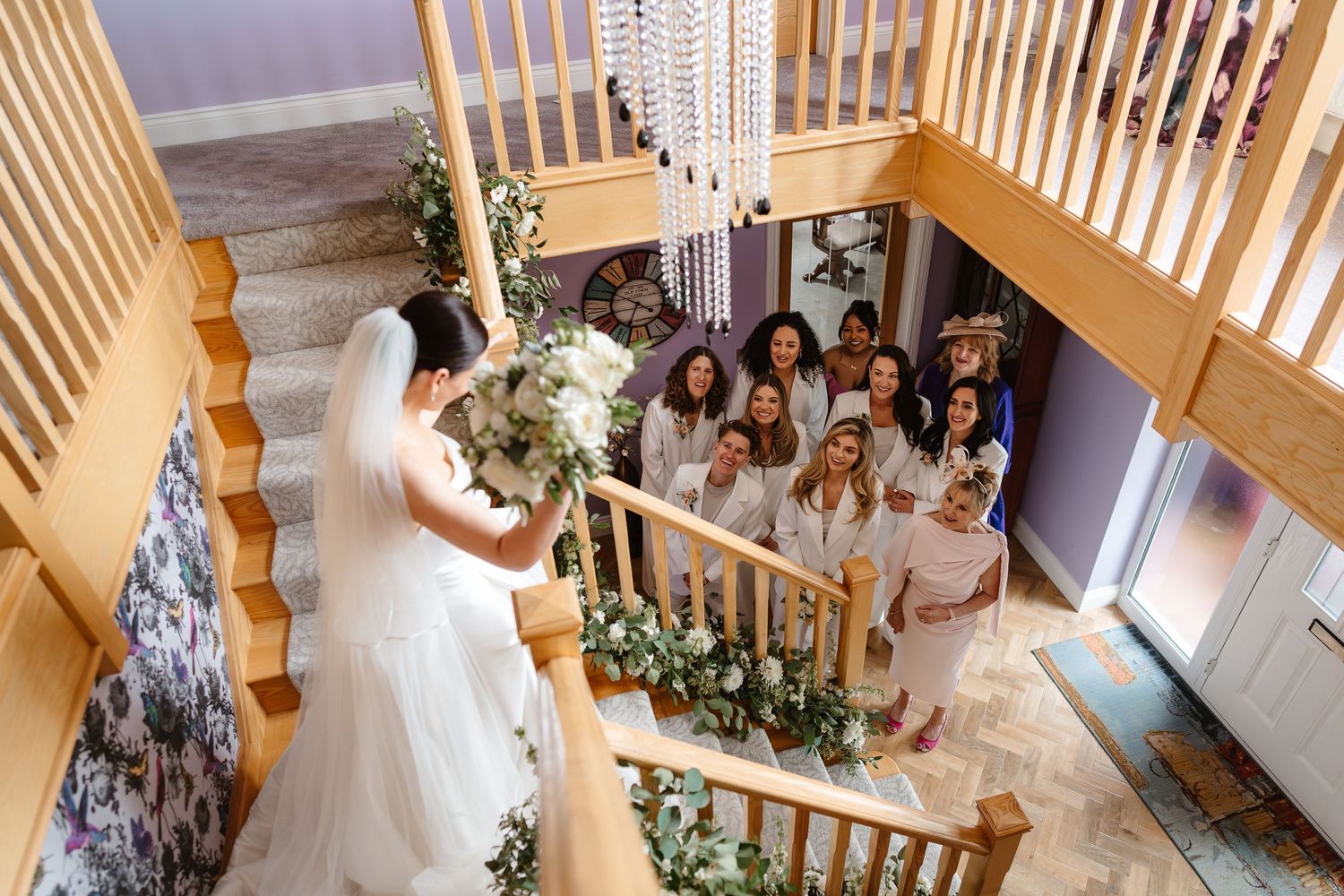 Elegant bridal first look entrance on beautiful staircase with mum and bridesmaids in suits. London wedding