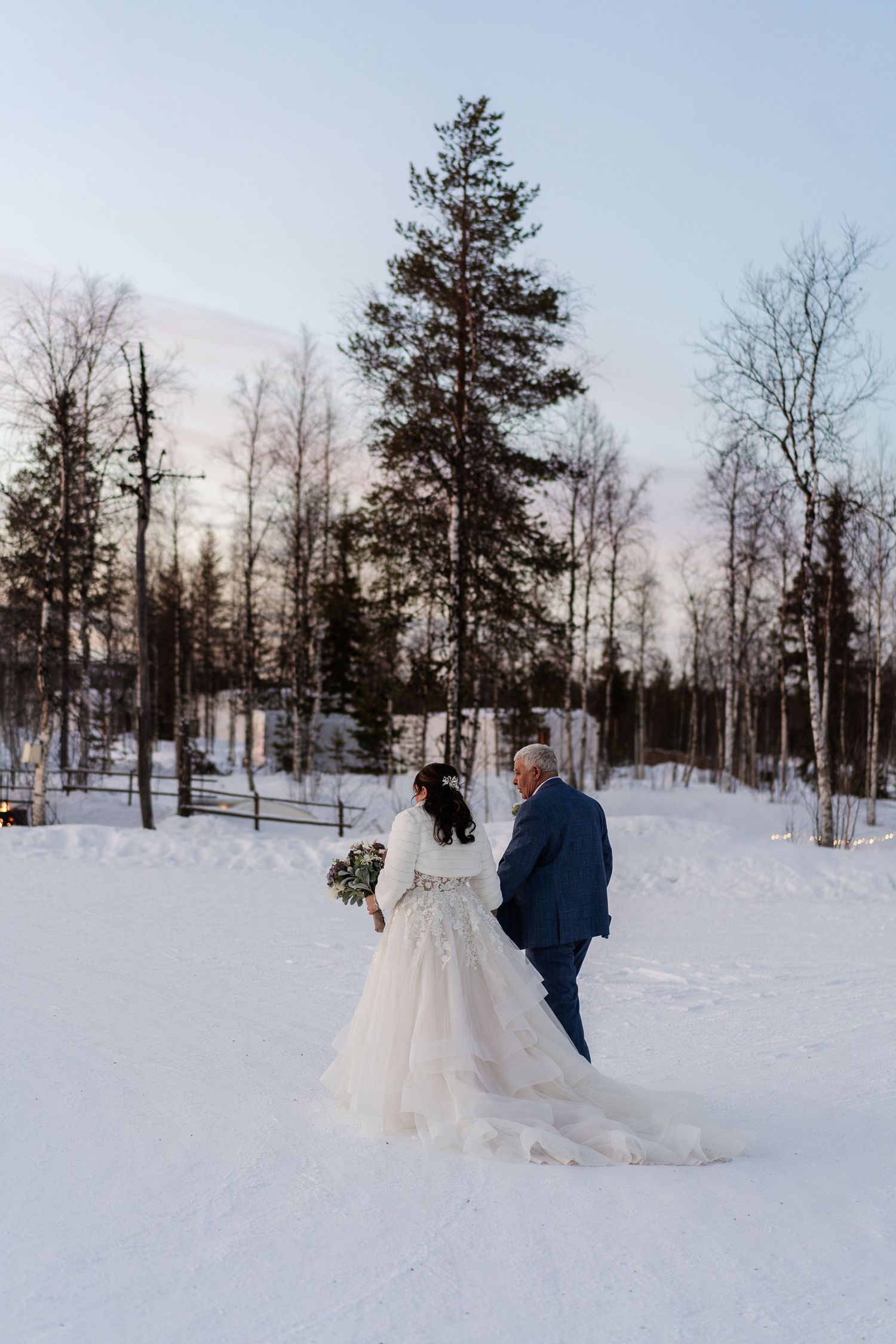 Couple candidly walking through forest at Snow Chapel, Levi. Luxury Lapland wedding photographer. Snow wedding. Mountain Wedding.