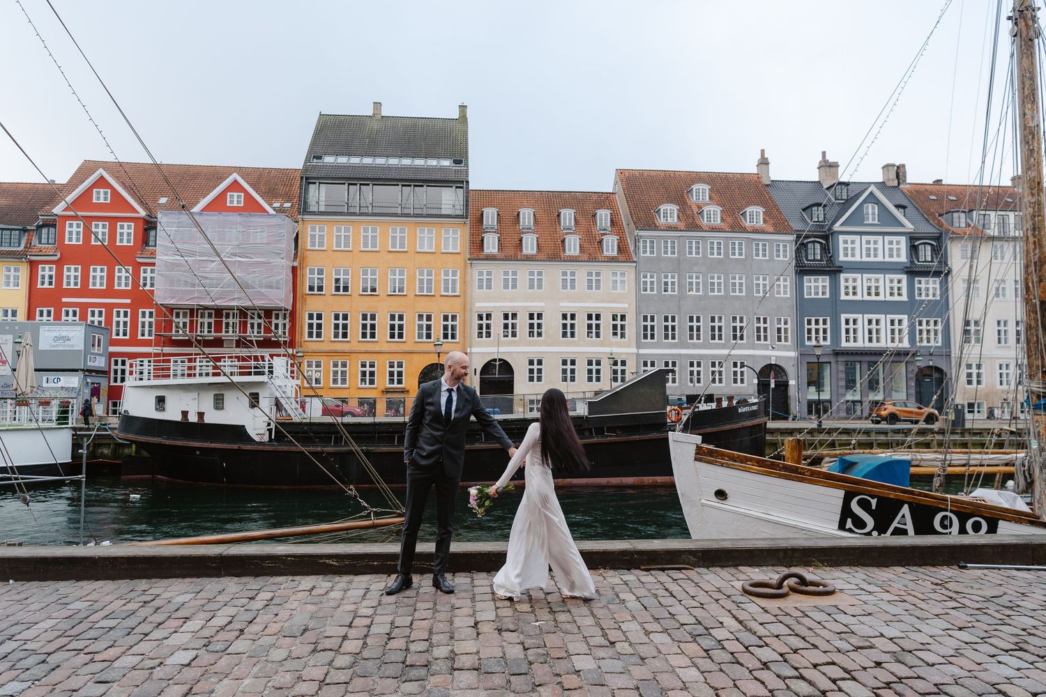 Newlyweds walking along Nyhavn Canal in Copenhagen. Denmark wedding. Scandinavian & Destination Wedding Photographer