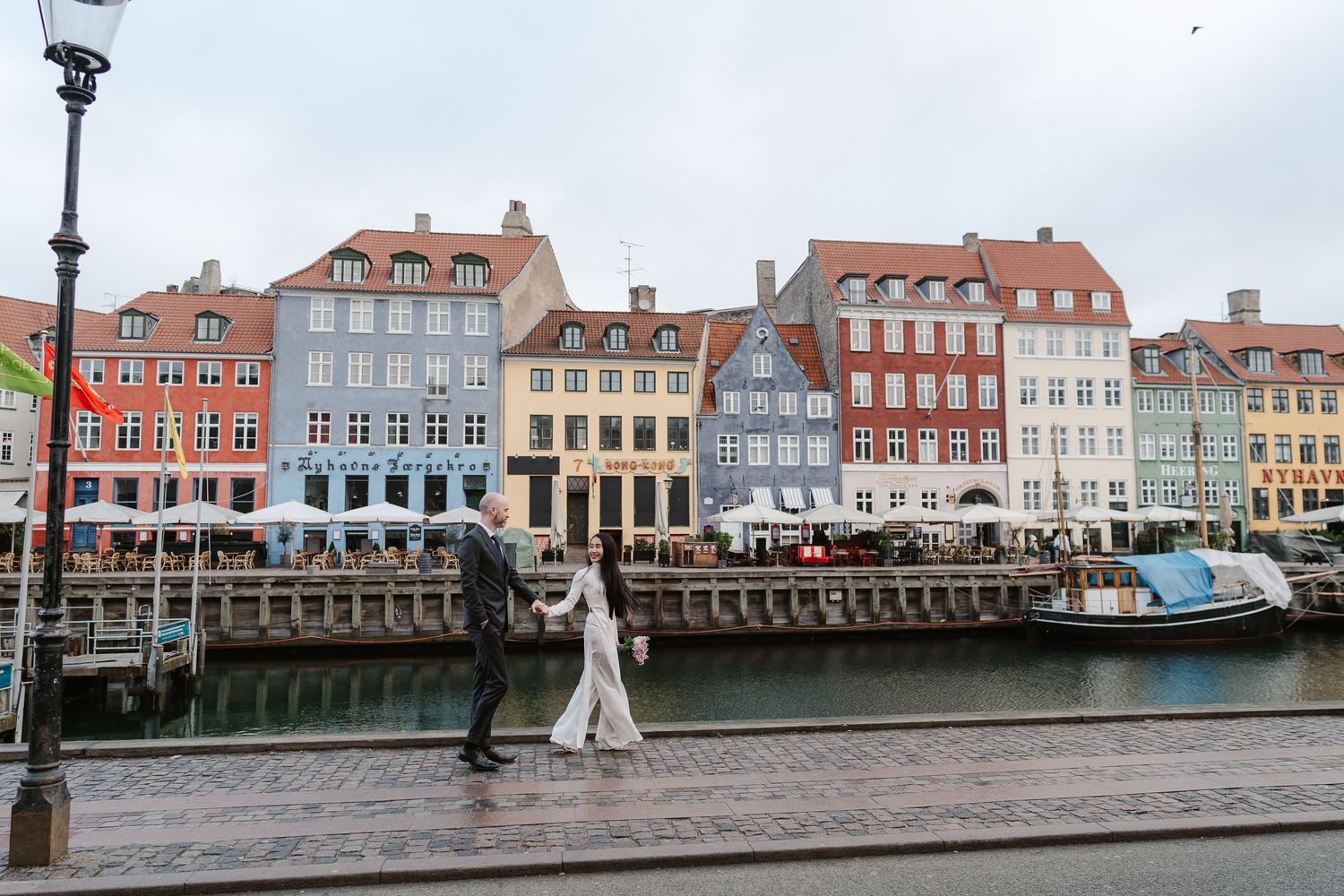 Newlyweds walking along Nyhavn Canal in Copenhagen. Denmark wedding. Scandinavian & Destination Wedding Photographer