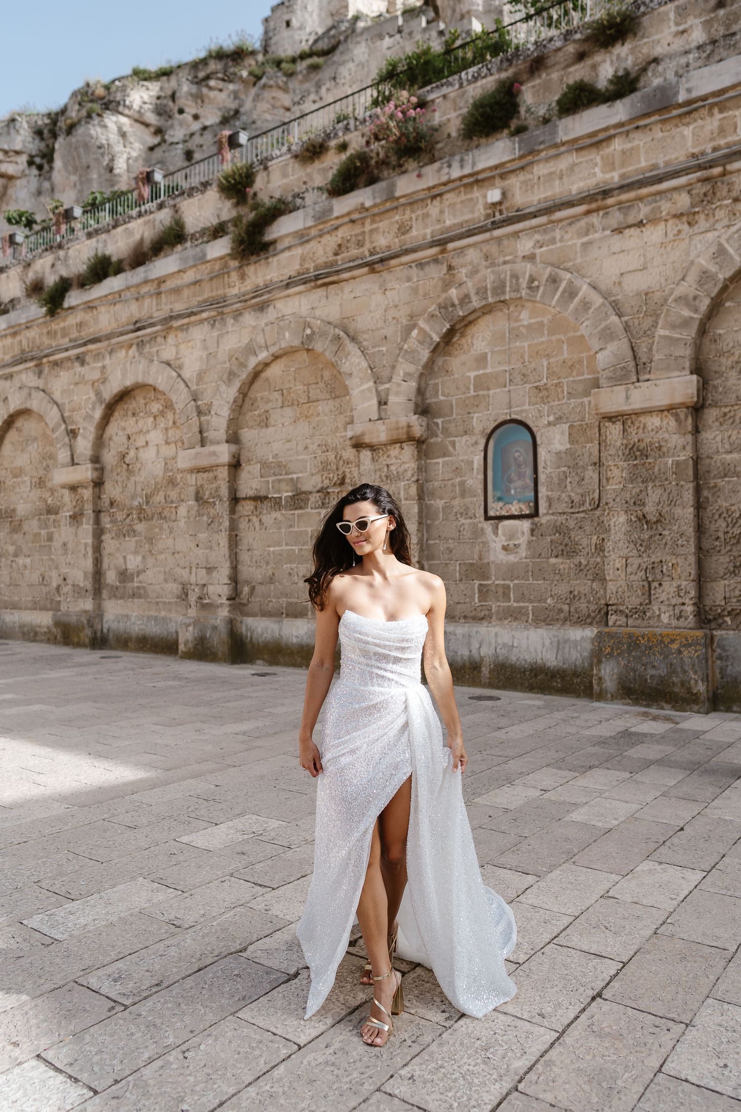 Strapless long flowing elegant dress - White fun heart shaped sunglasses, surrounded by old town walls. fun party vibe