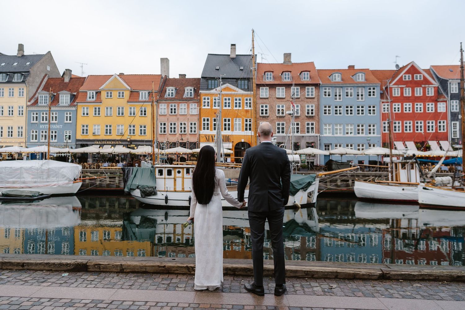 Newlyweds walking along Nyhavn Canal in Copenhagen. Denmark wedding. Scandinavian & Destination Wedding Photographer