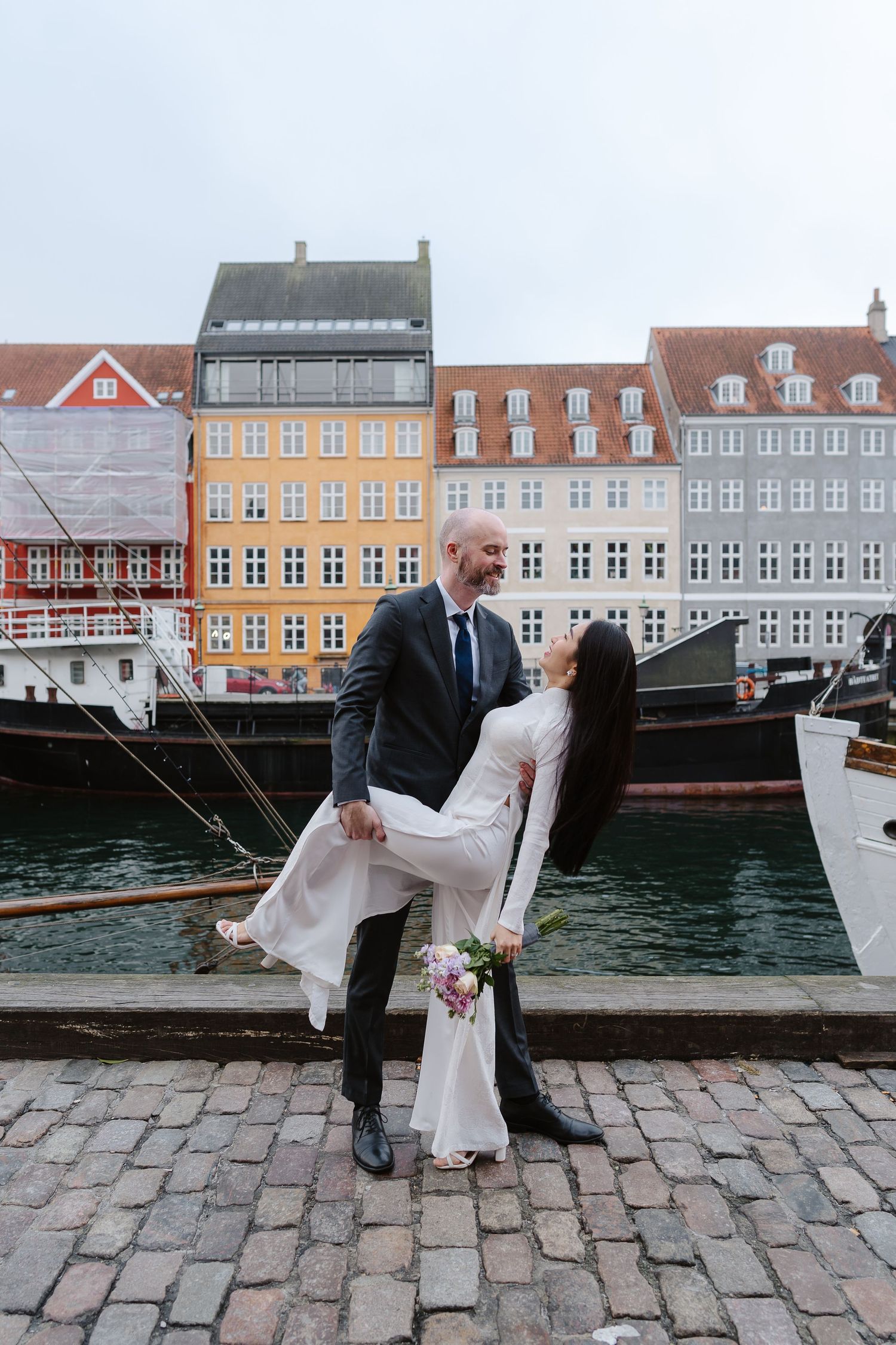 Newlyweds walking along Nyhavn Canal in Copenhagen. Denmark wedding. Scandinavian & Destination Wedding Photographer