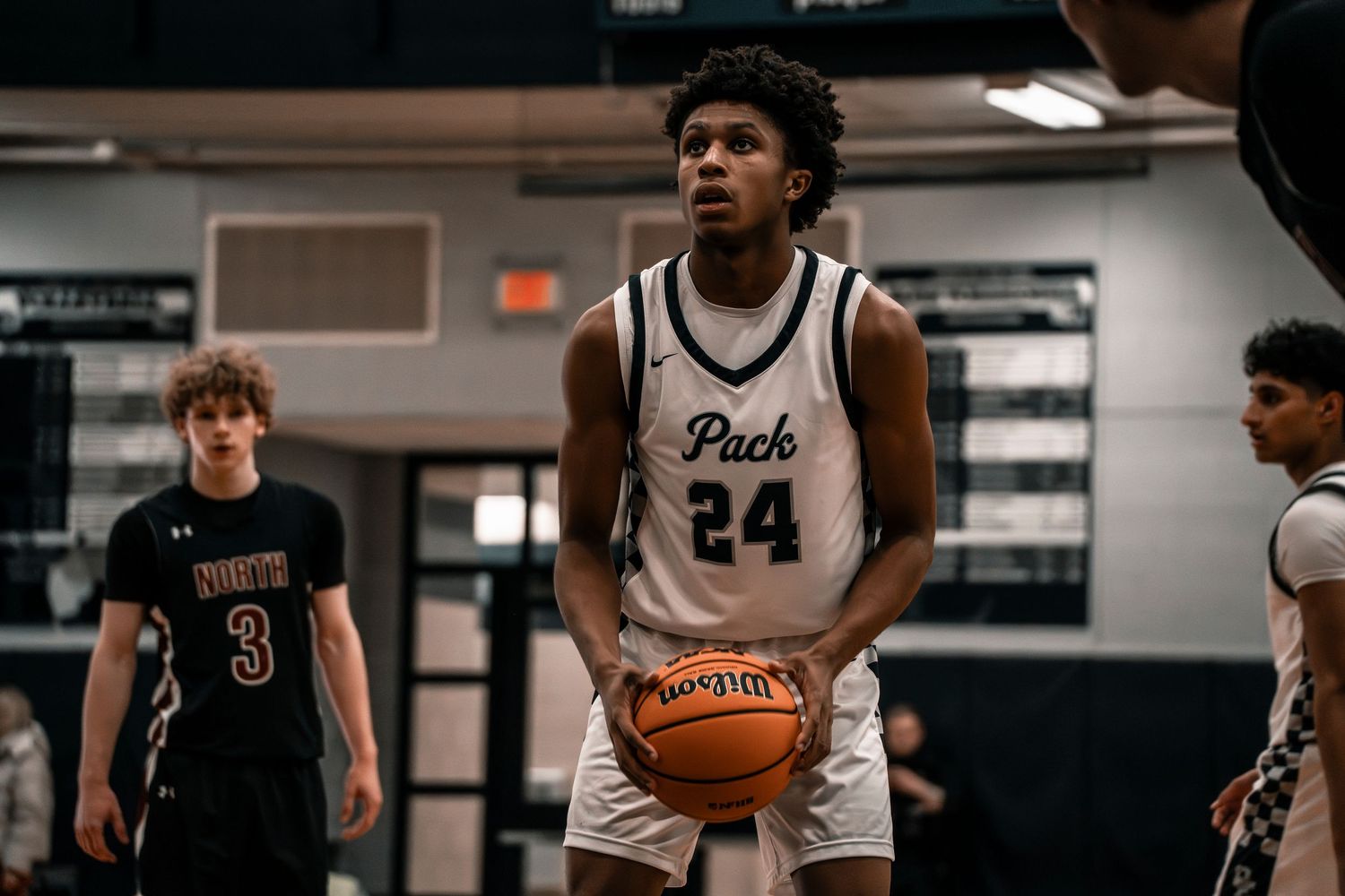 High school basketball player number 24 preparing for a free throw shot during an indoor game.