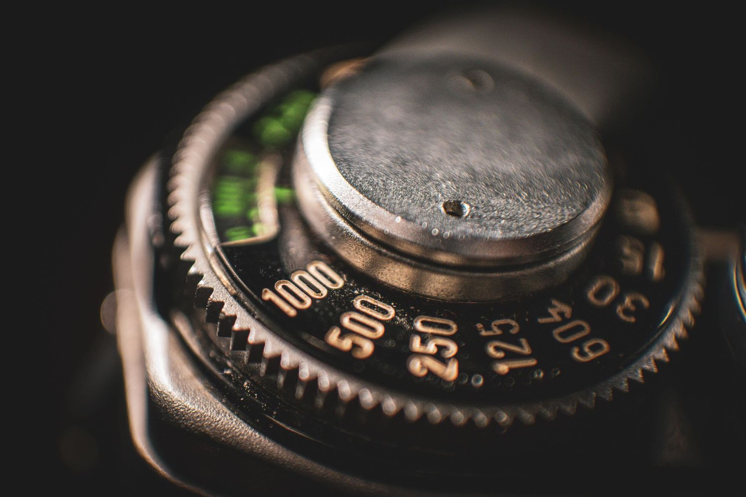 Close-up of a vintage camera shutter speed dial with numbers 125, 250, 500, 1000, showing aged metal texture.