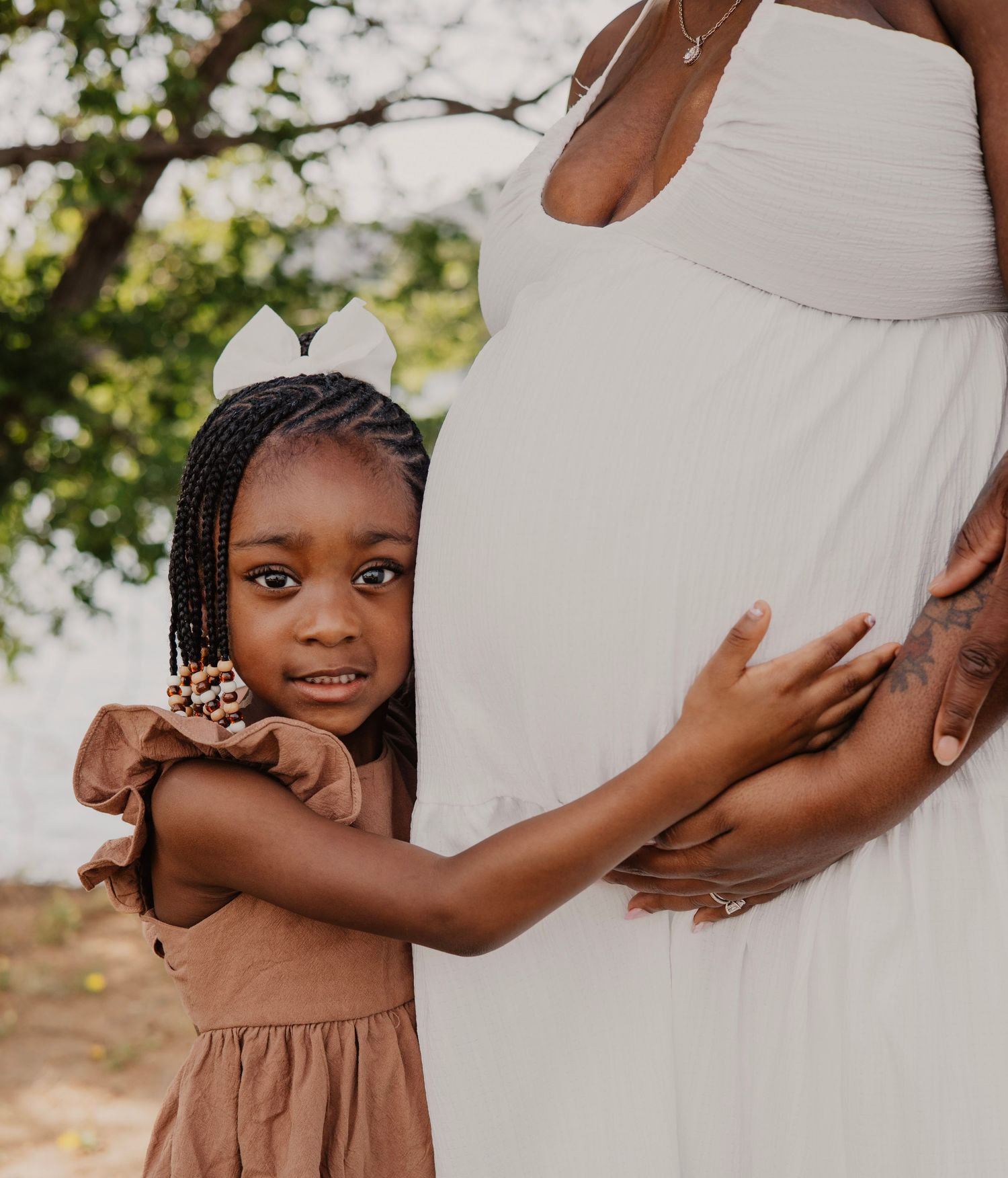 Maternity photo shoot with family members embracing a pregnant belly.