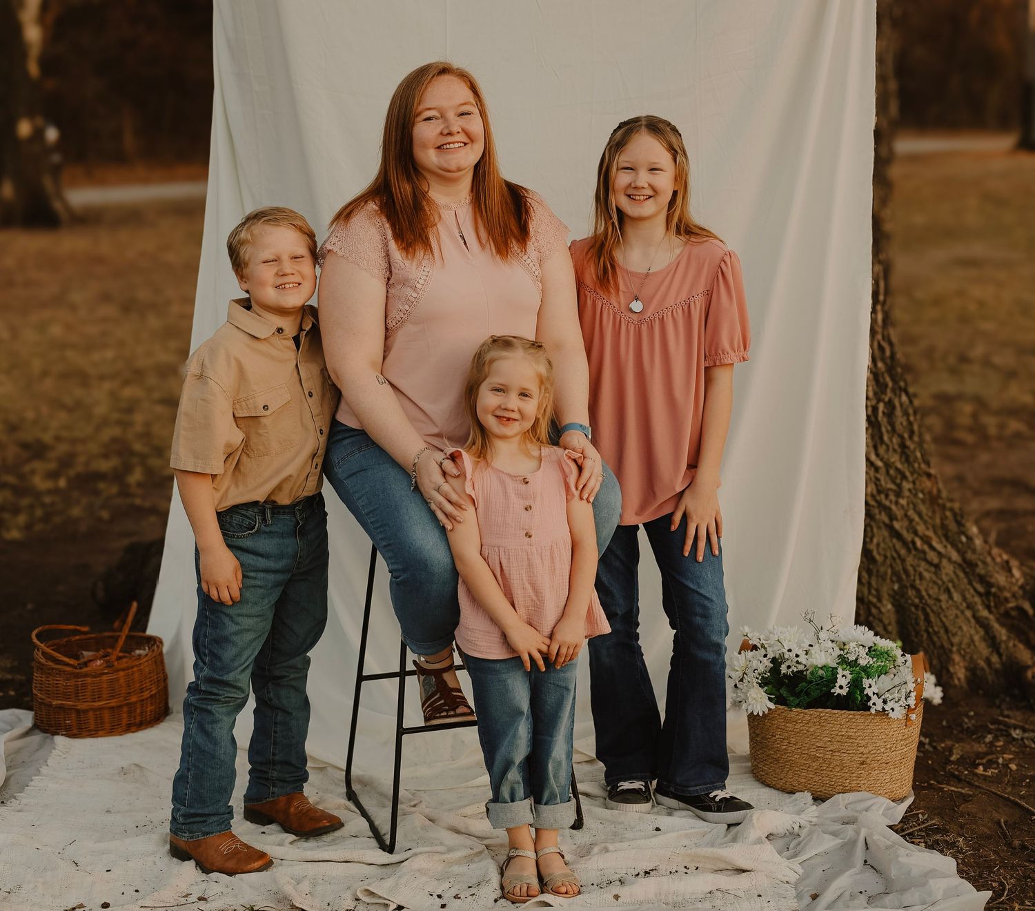 Family group poses casually together on white backdrop with rustic decor elements.