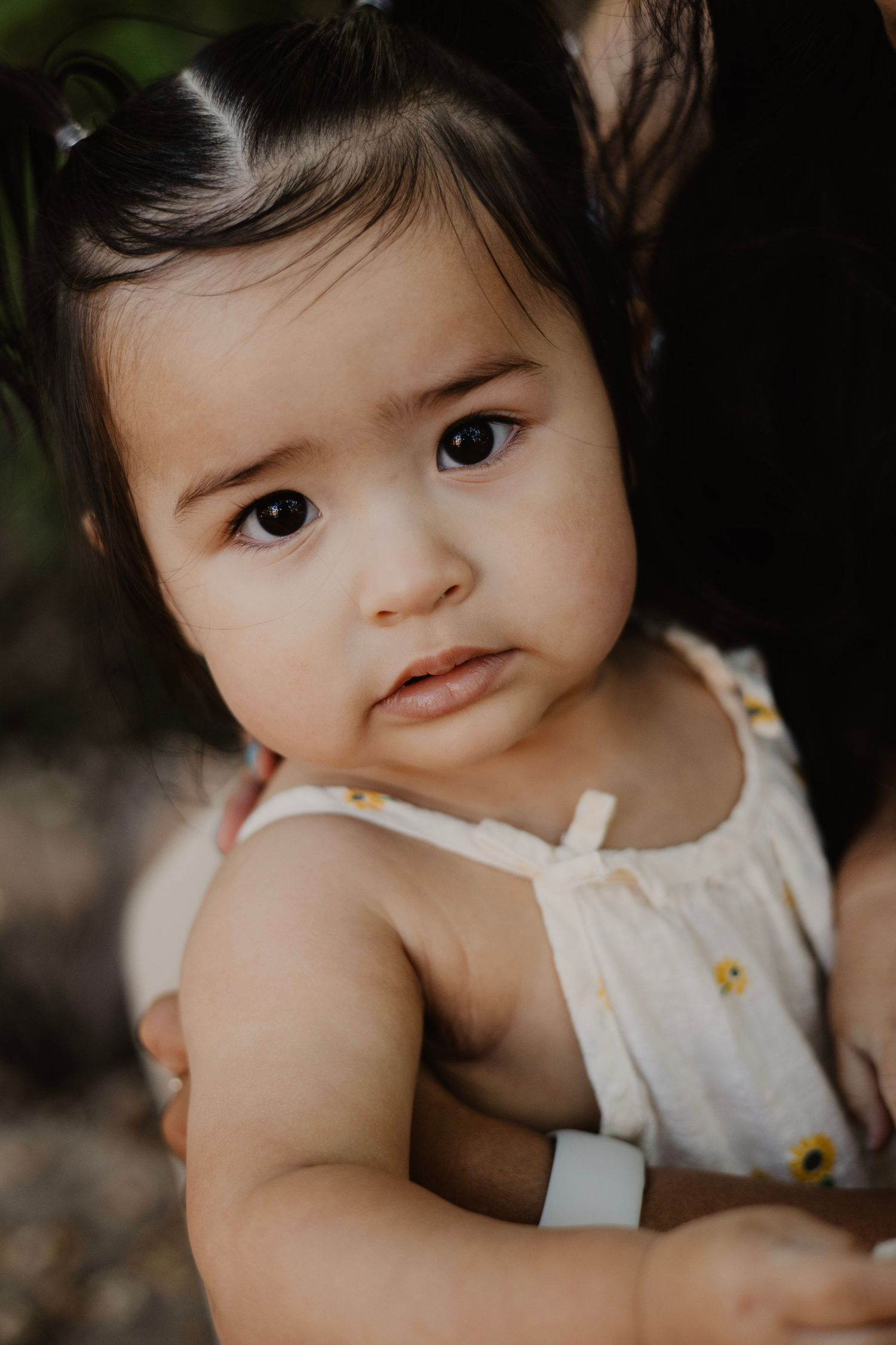 Baby in white sleeveless outfit poses for close-up portraits against dark background.
