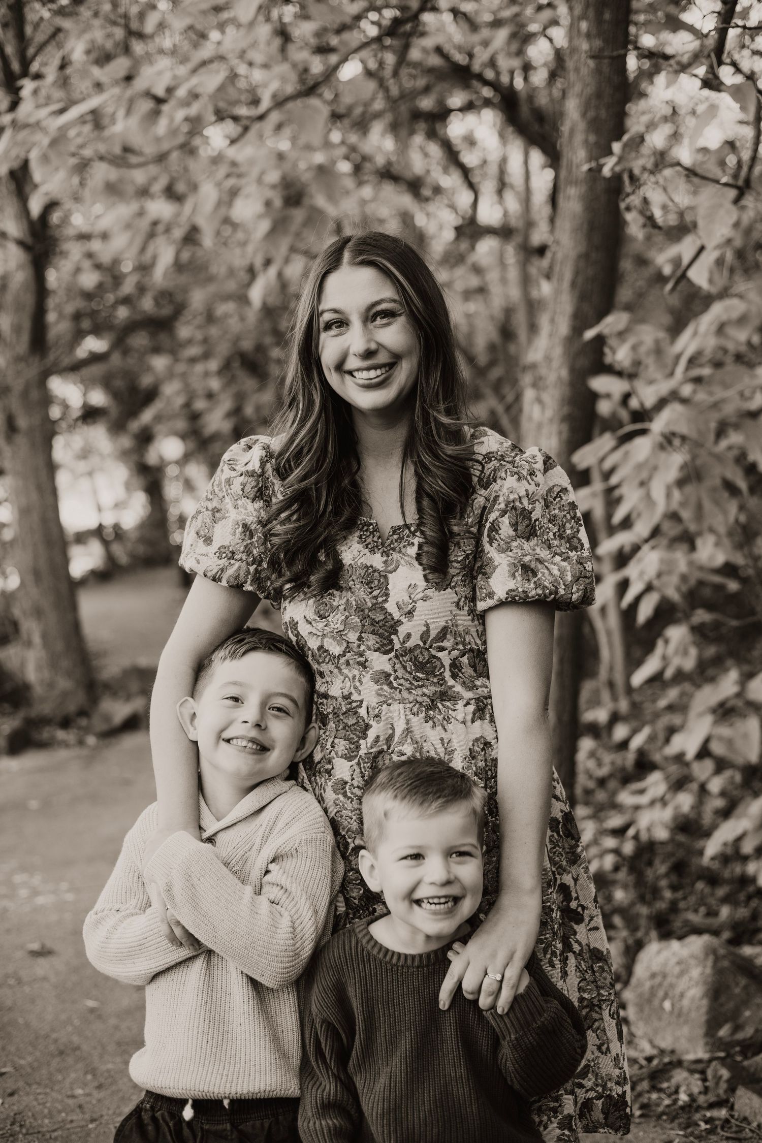 Black and white portrait of family group against leafy background.