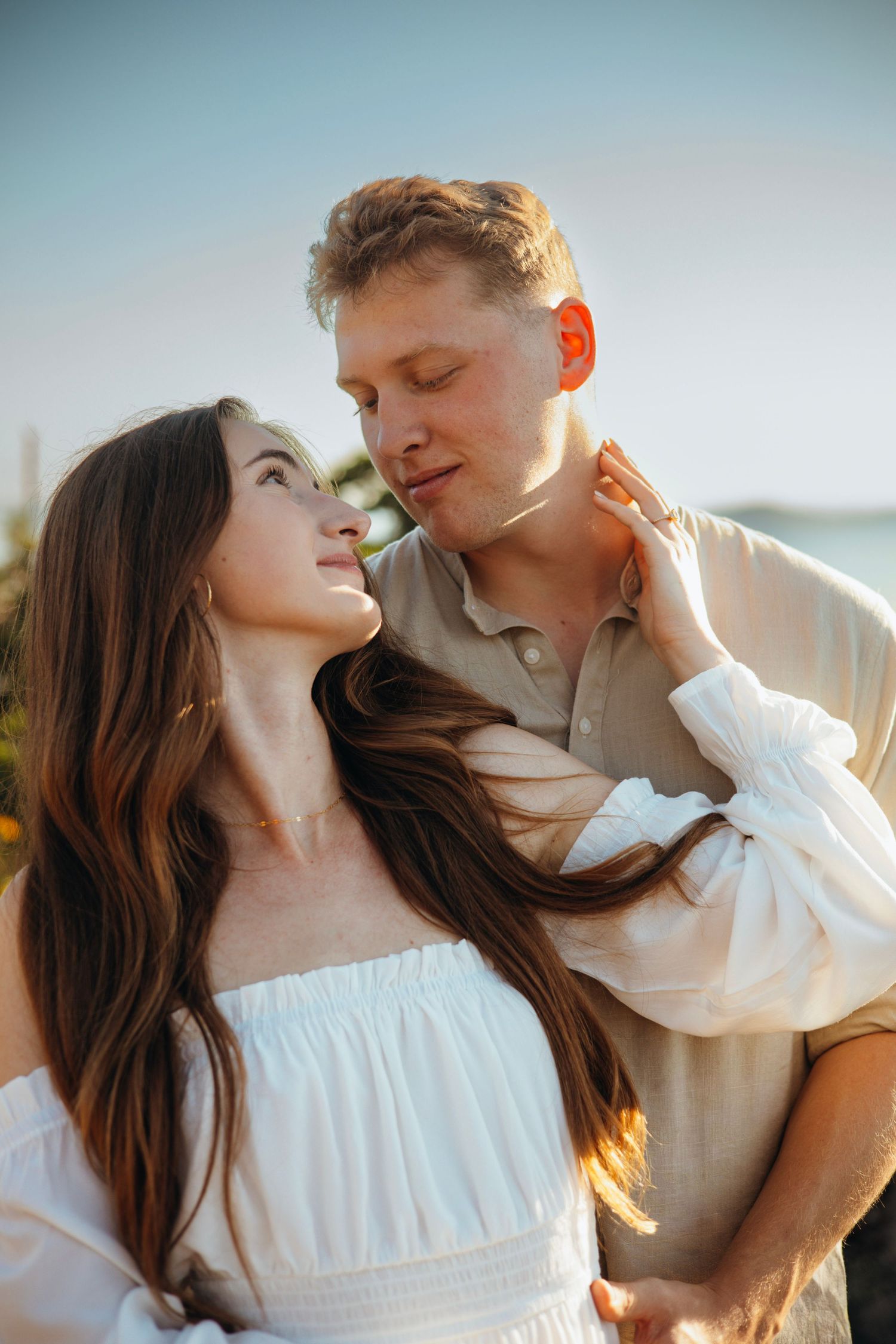An intimate moment between a couple in white clothing during golden hour.