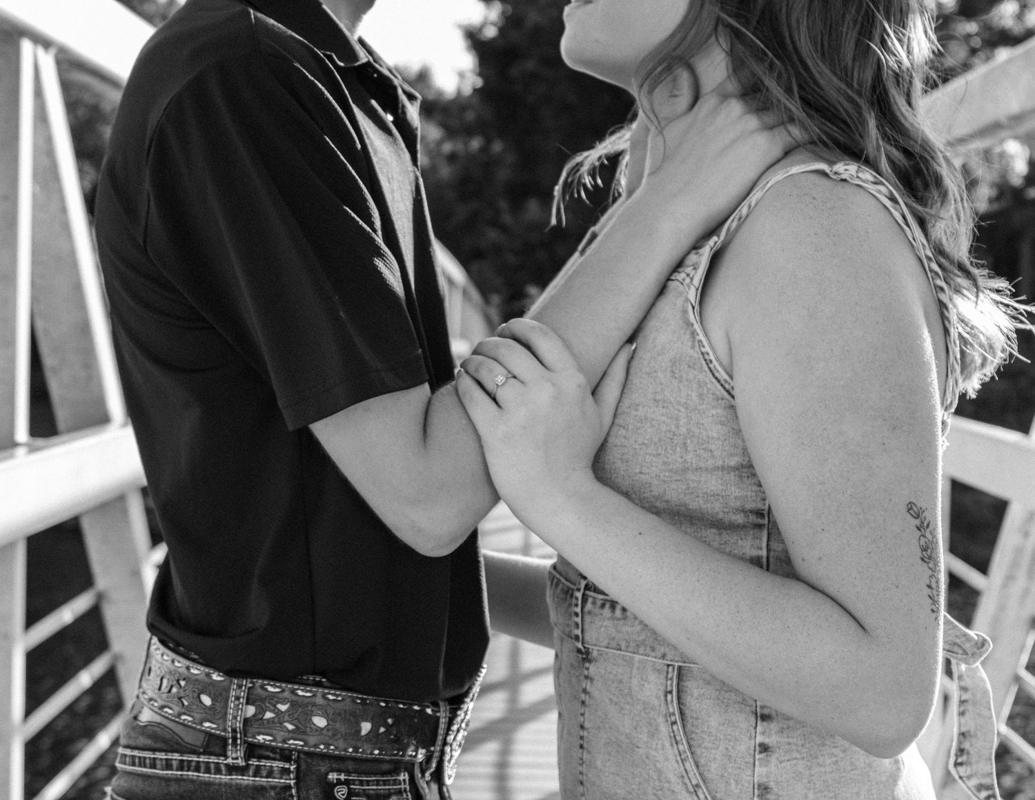 Black and white photo of a couple embracing on a porch with rustic details.
