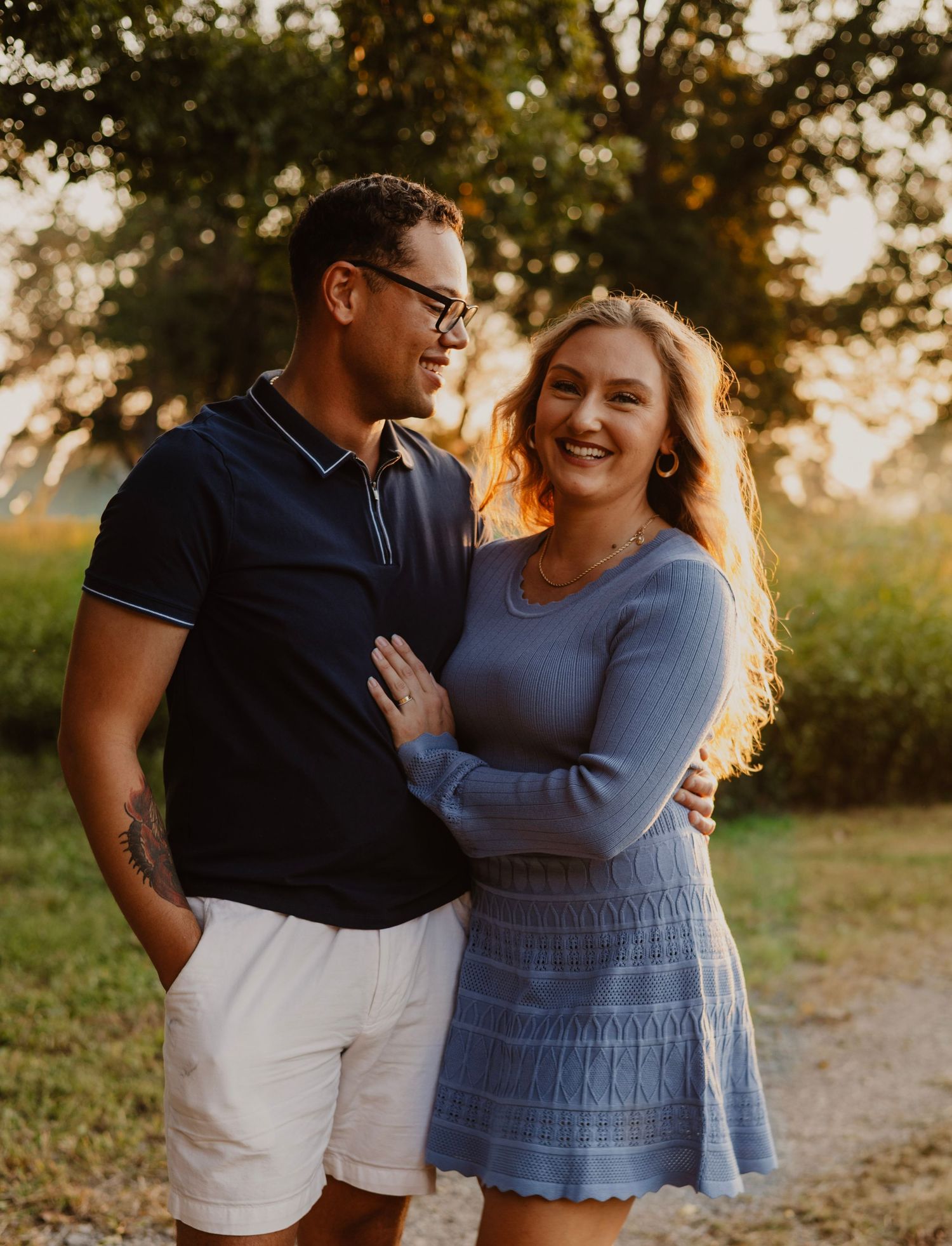A joyful couple sharing a laugh together in a sunlit outdoor setting.