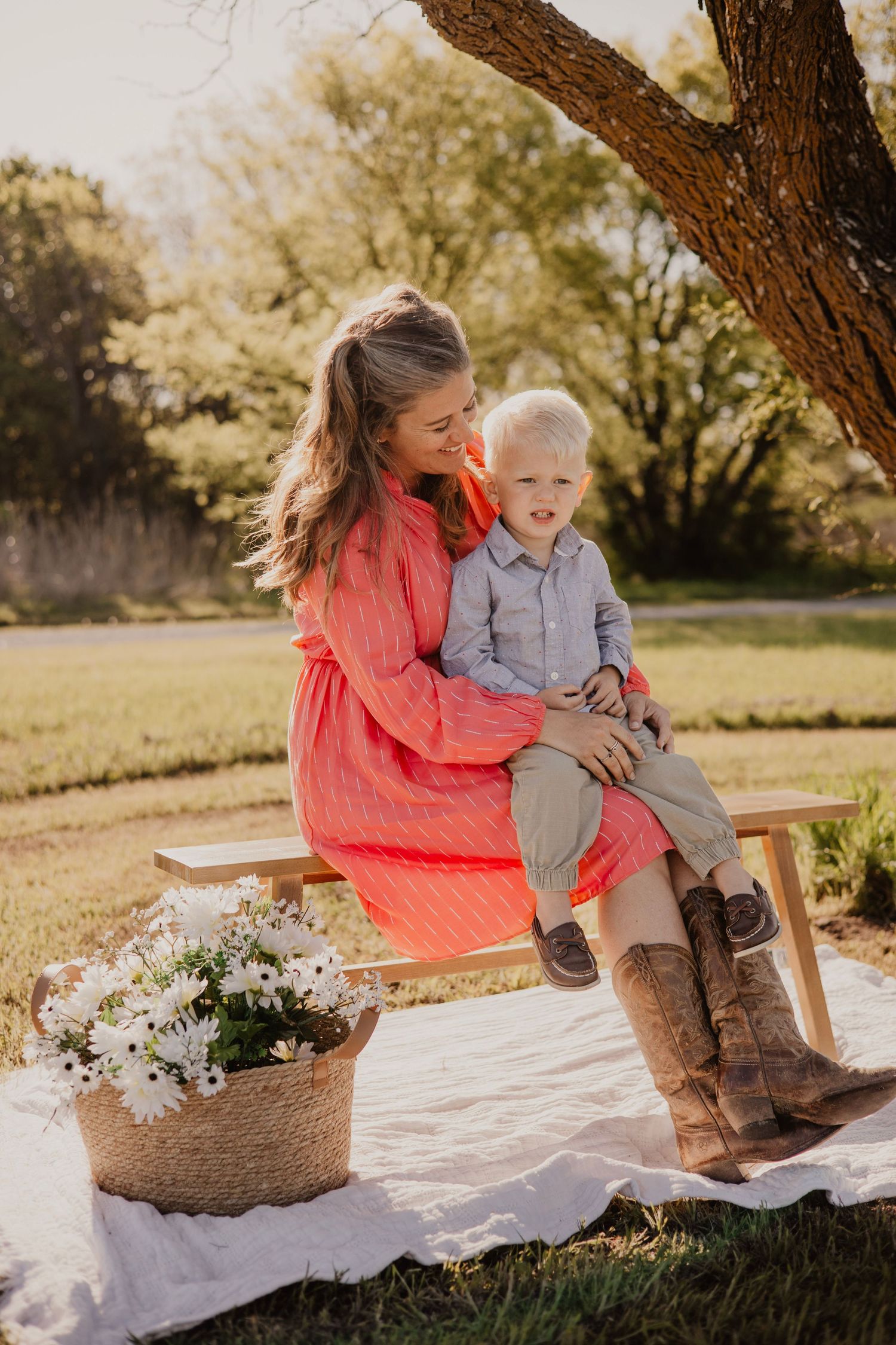 A picturesque outdoor scene with two people sitting on a wooden bench next to a basket of white daisies at sunset.