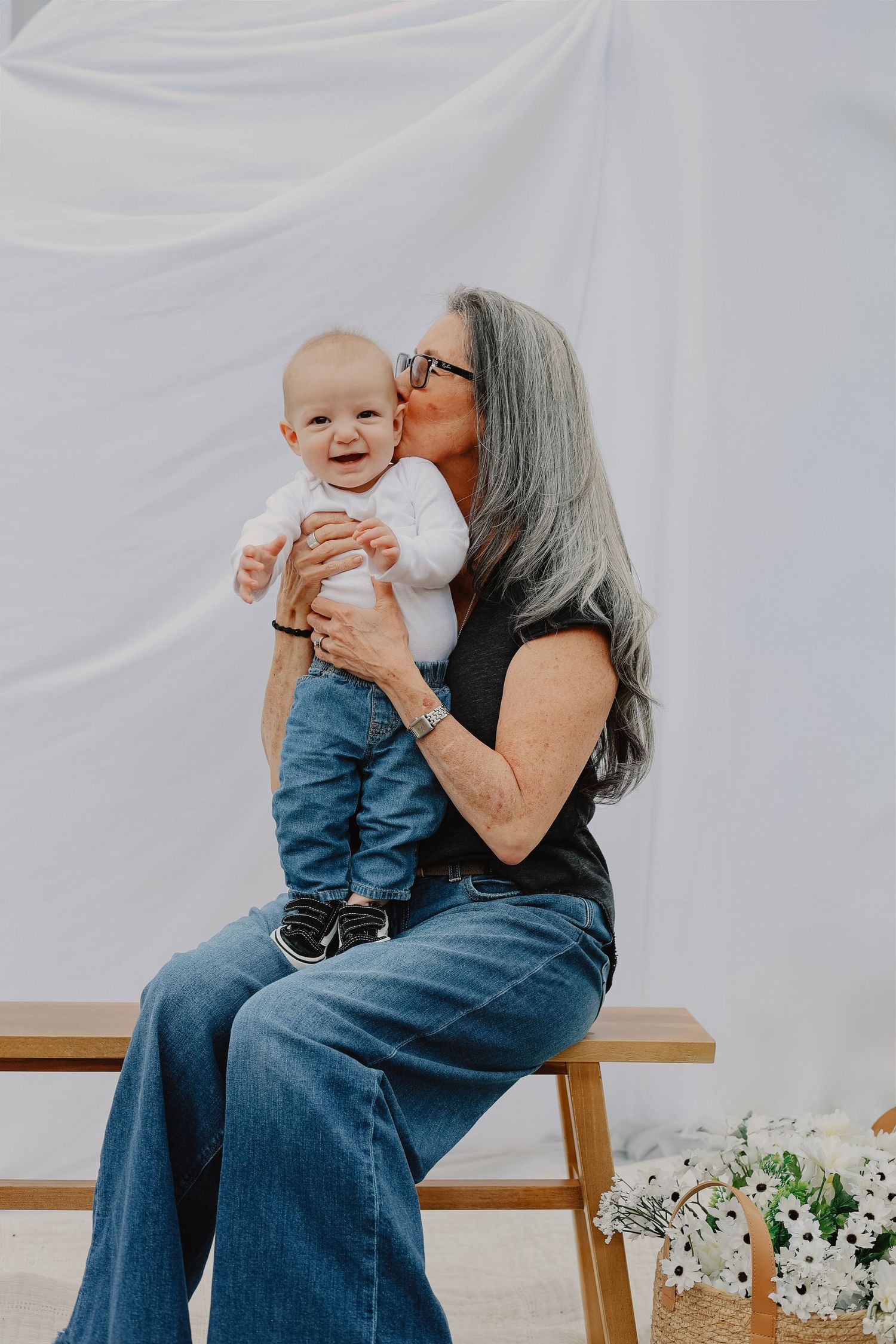 Candid family moments captured on wooden bench with white backdrop.