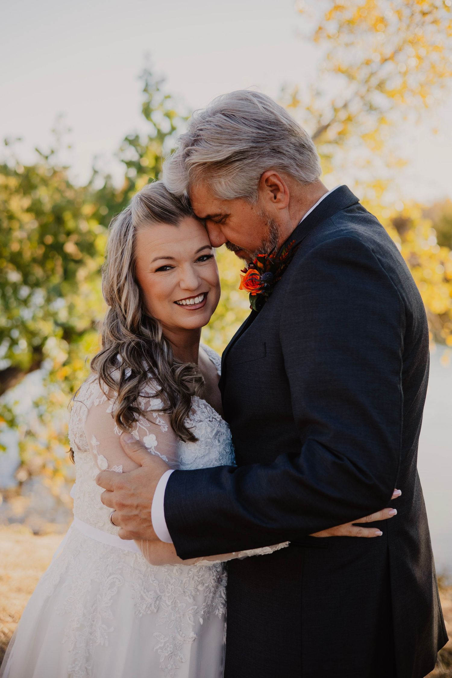 Romantic wedding portraits captured during golden hour with autumn colors in background.